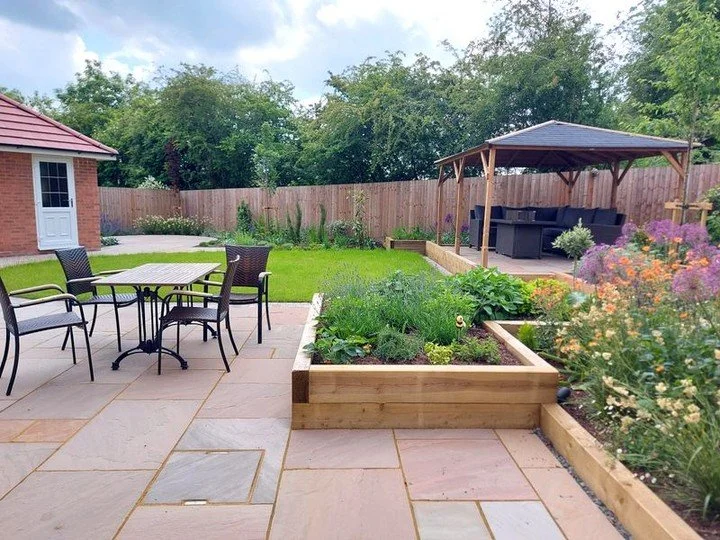 Adding style to a new build garden plot. On a slight slope, this site needed to be terraced to allow for level areas of paving and space for a covered gazebo for entertaining. The simple and cost effective use of sleepers allowed for additional plant