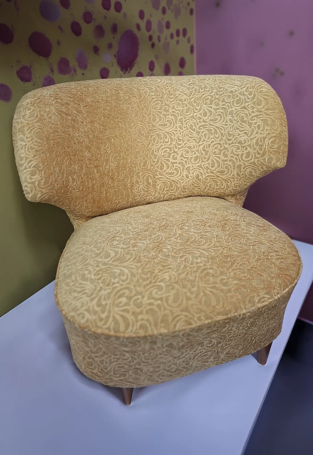 Verhoomo Kultatuolin verhoilema nojatuoli koristeellisella kullansävyisellä kankaalla.
