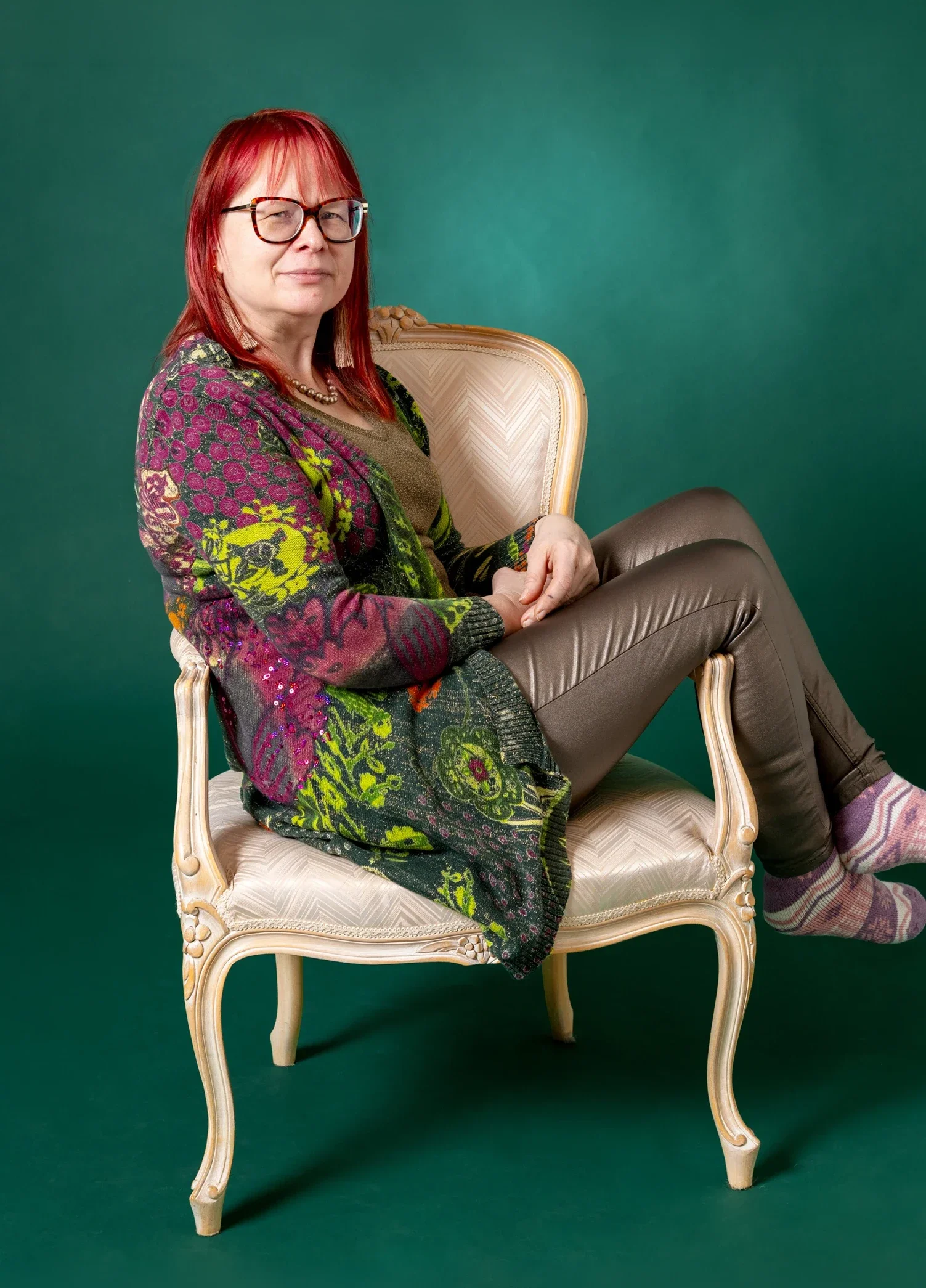 Verhoilija Irene Nieminen Verhoomo Kultatuolista istumassa kauniissa vanhassa nojatuolissa.