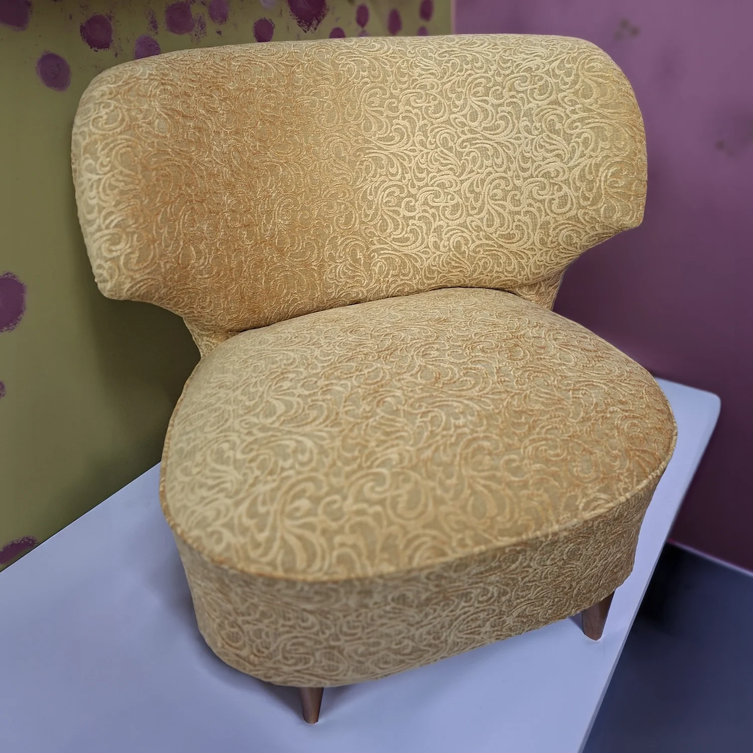 Verhoomo Kultatuolin verhoilema nojatuoli koristeellisella kullansävyisellä kankaalla.