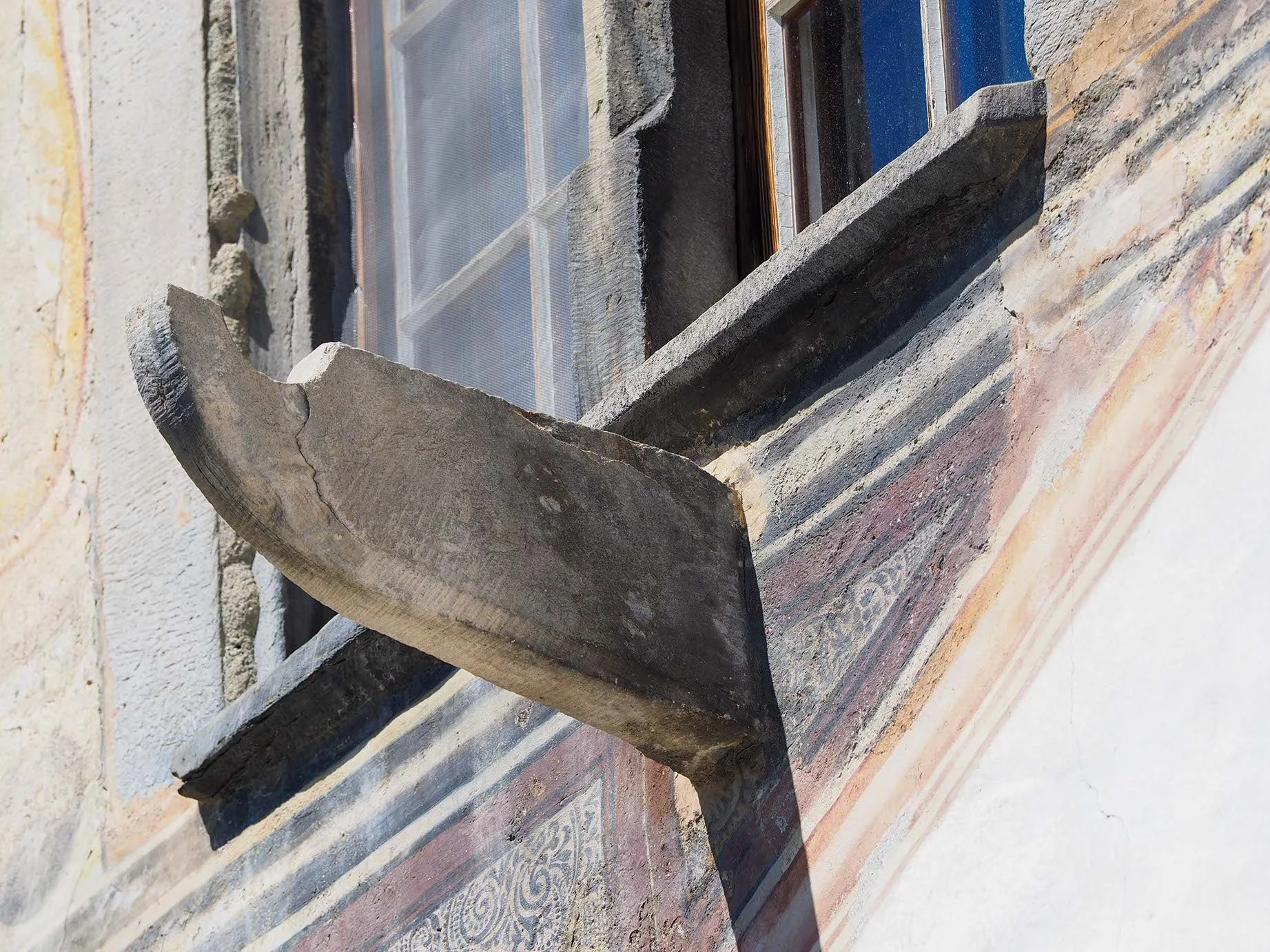 Der Bildausschnitt zeigt einen Bauarbeiter, der in einem alten, steinernen Fensterrahmen mit einer dämmenden Schutzfolie arbeitet. Die Baustelle befindet sich wahrscheinlich in einem Gebäude im Umbau.
