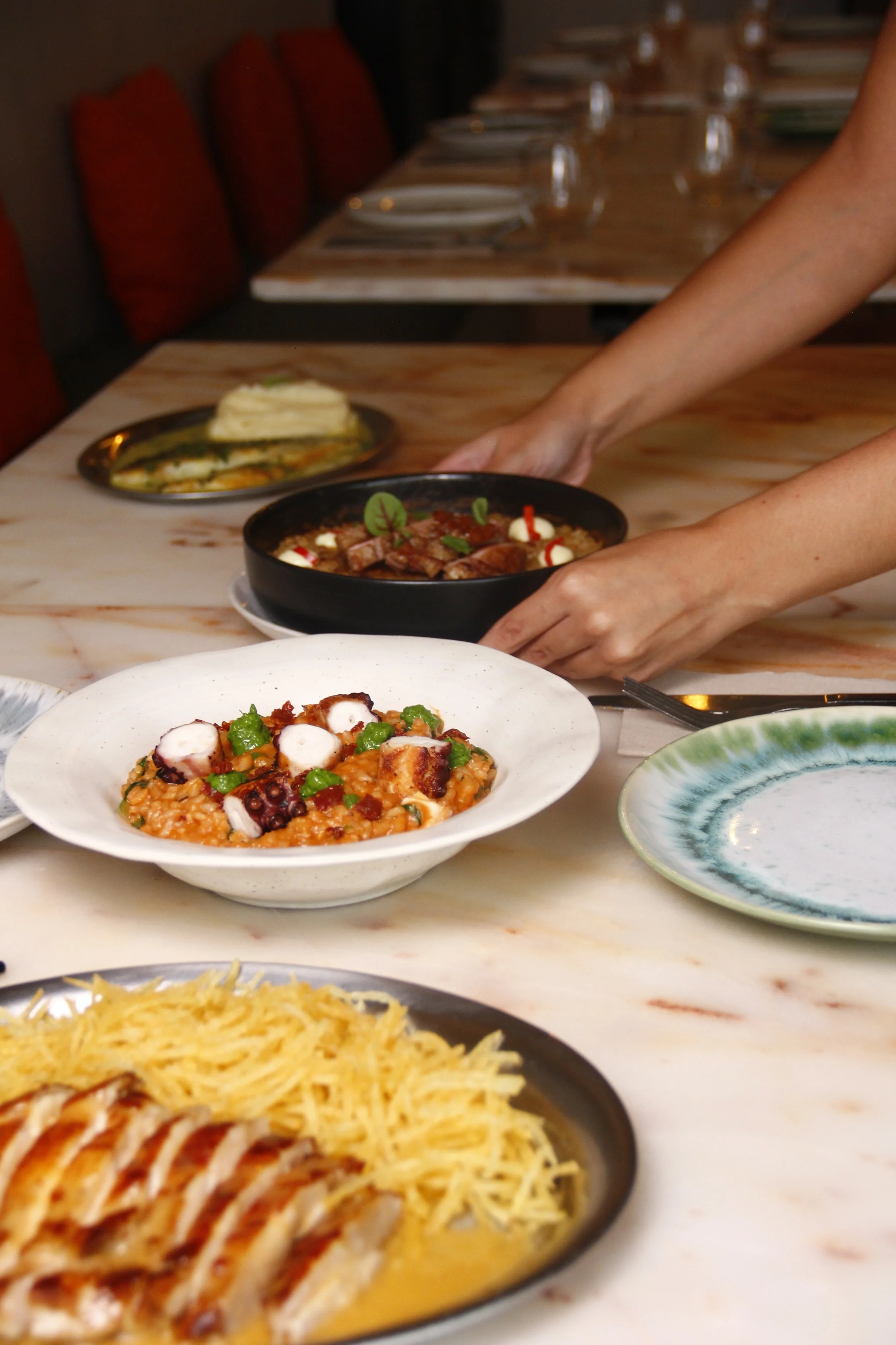 Pessoas a servir pratos de comida bem apresentada e com aspeto delicioso numa mesa do restaurante Cobaia em Alvalade, Lisboa.