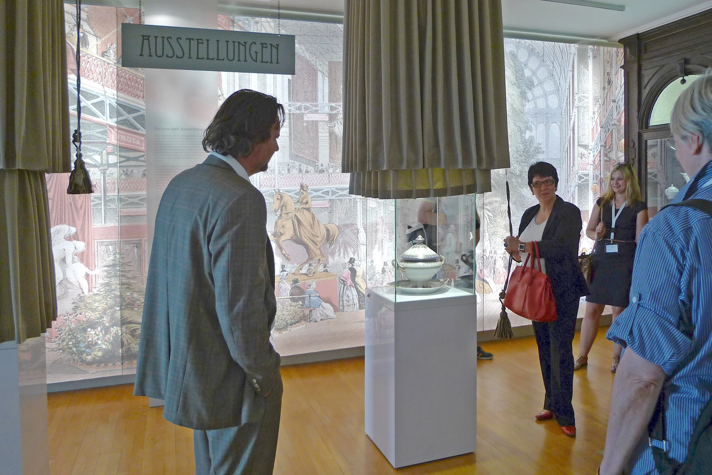 Menschen betrachten eine Ausstellung mit einer antiken Schale in einem Museum.