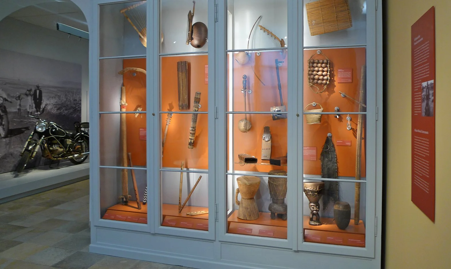 Vitrine mit arten von ethnografischen Gegenständen, darunter Musikinstrumente, Körbe, Töpfe, Werkzeuge und Stoffe, im Museum ausgestellt.