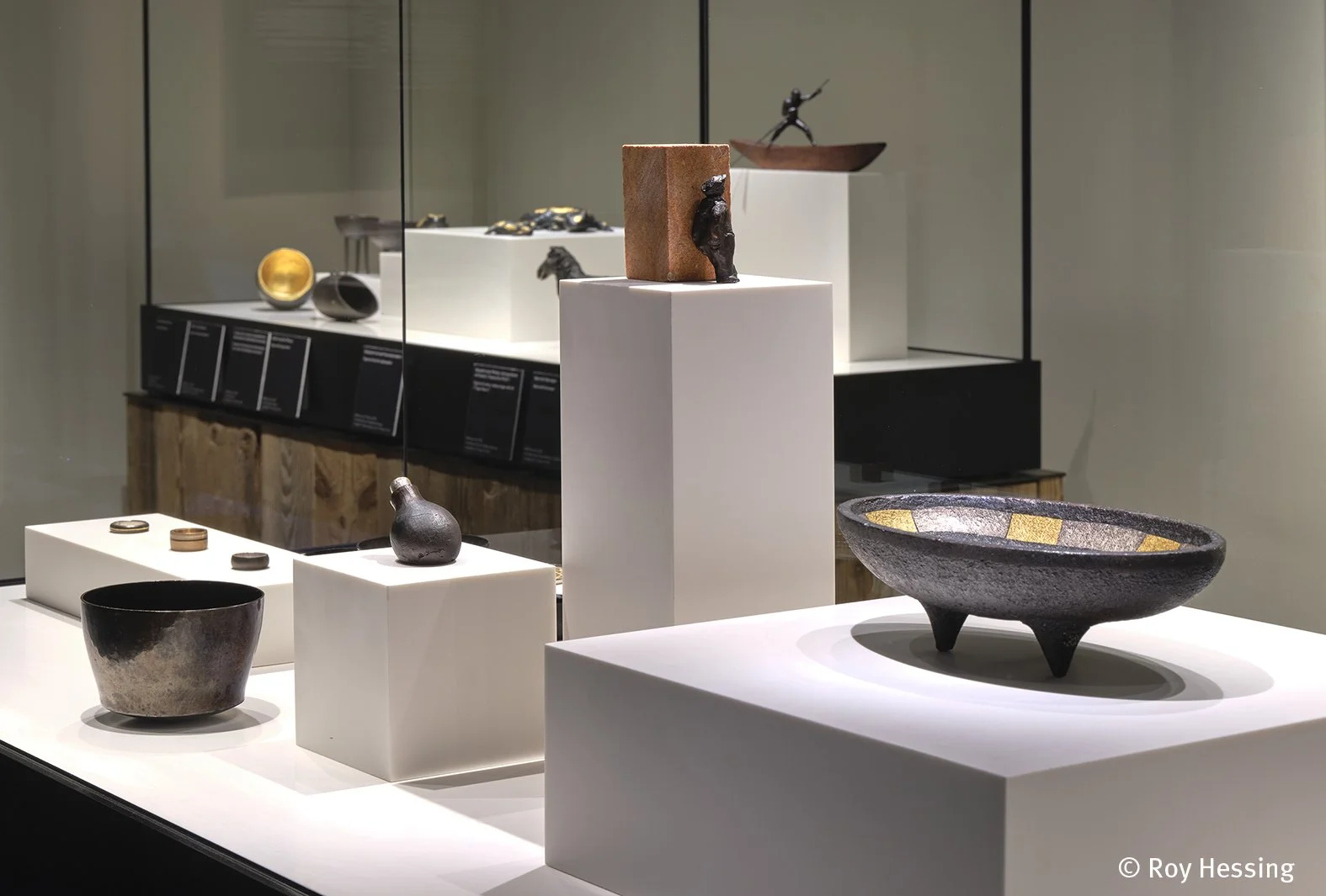 Ausstellung mit keramischen Skulpturen und Artefakten auf weißen Podesten in einem Museum.