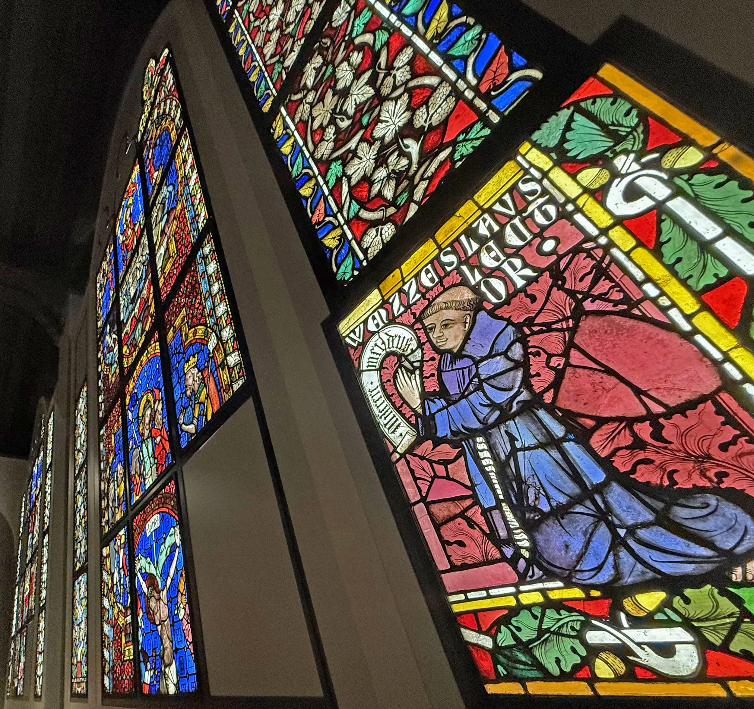 Fenster mit bunten Glasfenstern, die religiöse Szenen und Figuren darstellen, in einer Kirche.