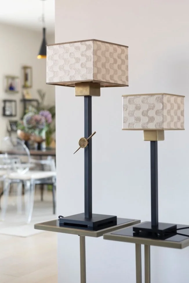 Two modern table lamps with square fabric shades and black bases, placed on small tables in a contemporary interior setting.