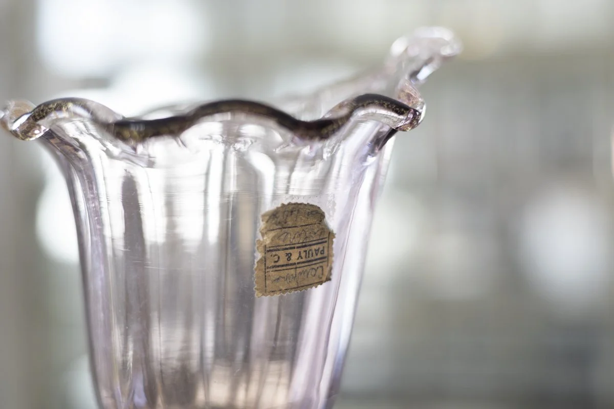 Close-up of a decorative glass bowl with a wavy edge and a label inside.