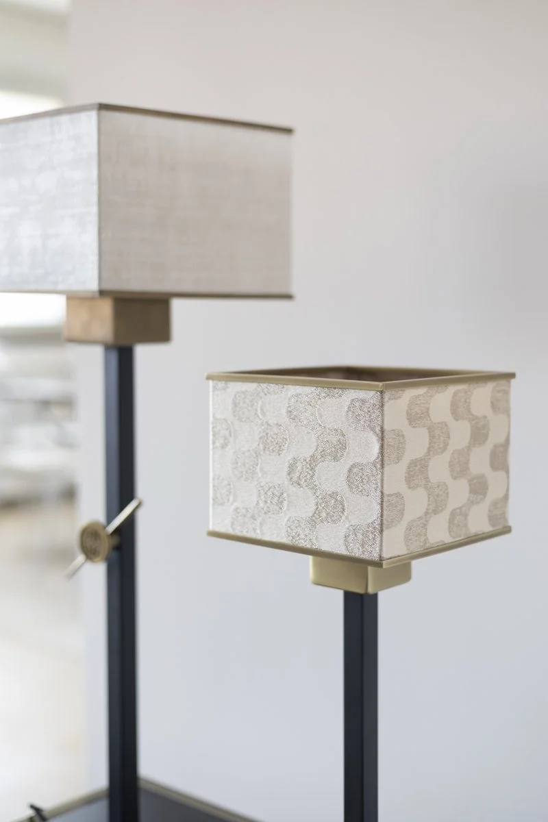 Two standing lamps with fabric shades on a plain, light-colored wall.