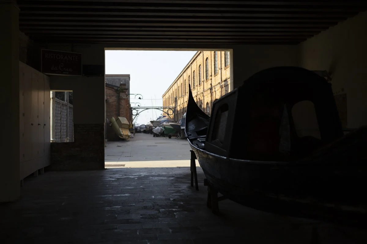 View through an archway showing boats on water and buildings outside.