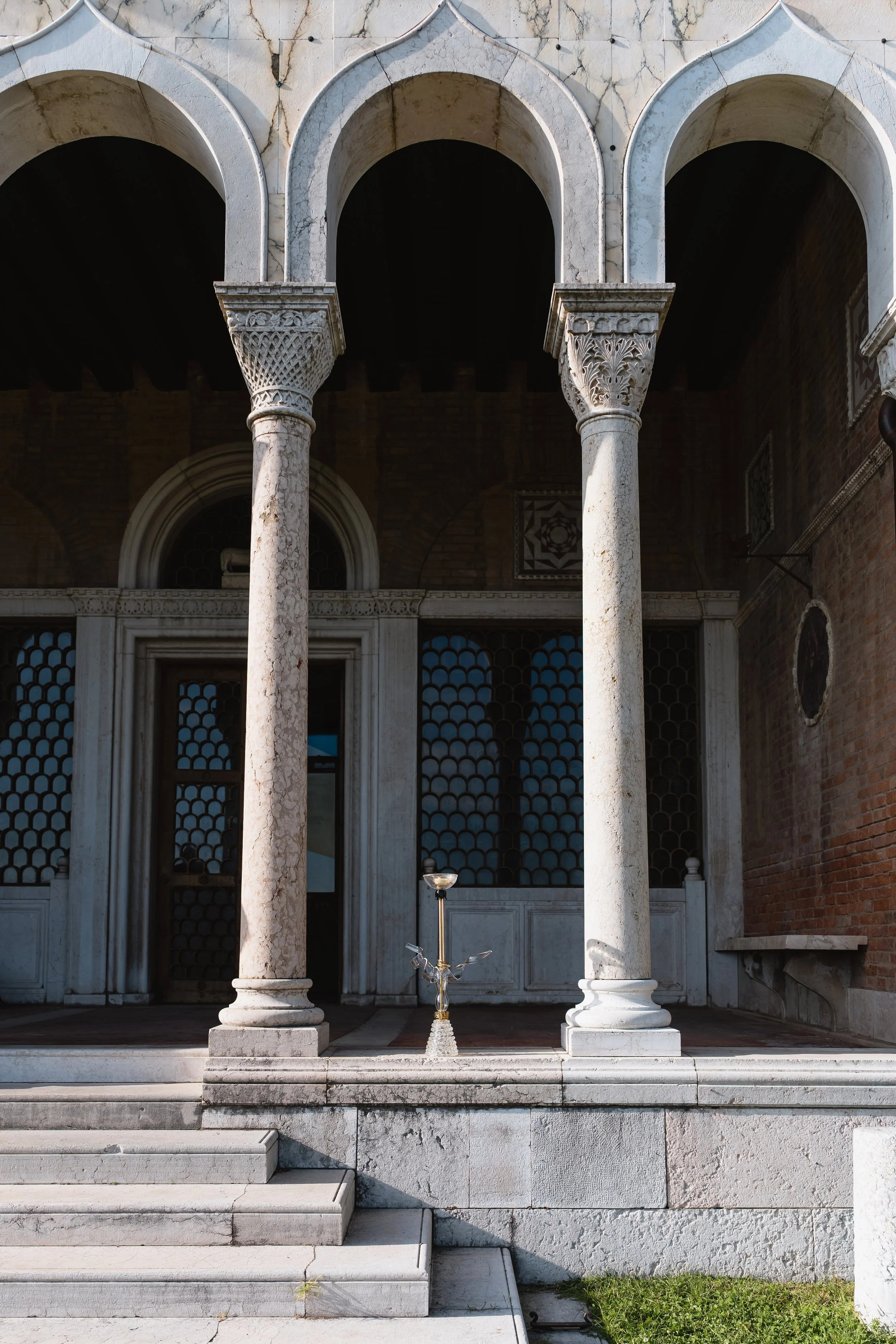 Front view of a historic building with three marble arches supported by marble columns, steps leading up to the entrance, and a decorative hookah in the center of the steps.