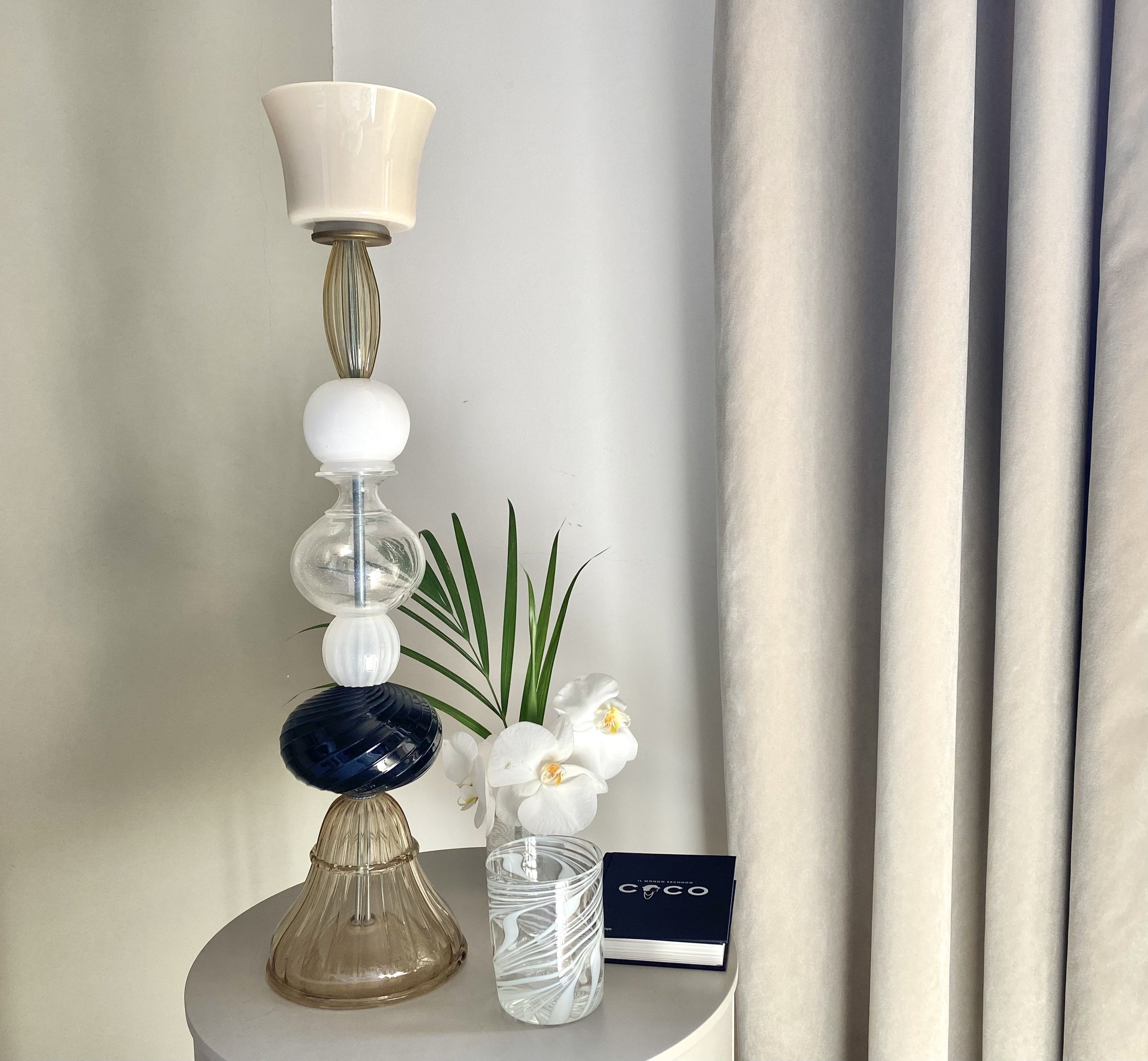 Decorative glass vases with a flower and a set of glasses on a white surface.