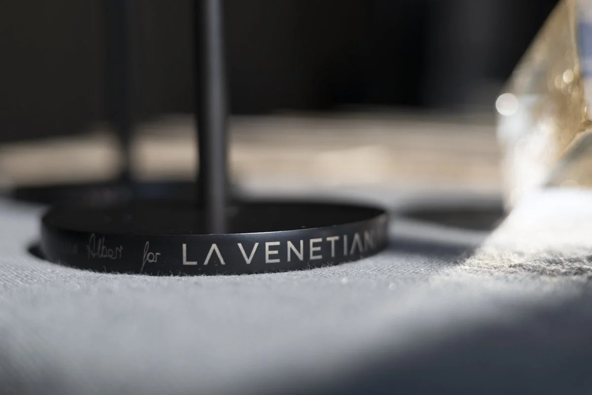 Close-up of a circular black object with the text 'LAVENTIAN' and some handwritten script on it, placed on a light-colored surface.