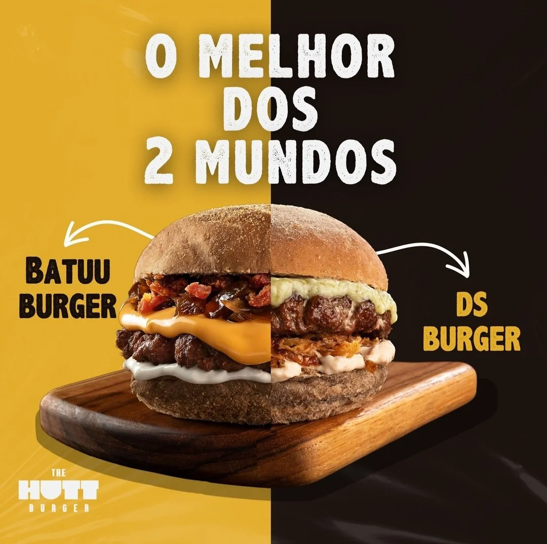 Imagem de um hambúrguer dividido ao meio, mostrando dois tipos diferentes de hambúrgueres, com texto em português que diz "O melhor dos 2 mundos": à esquerda, "Batuu Burger" com carne, queijo, bacon e molhos, e à direita, "Ds Burger" com carne, queijo e molho branco, sobre uma tábua de madeira.