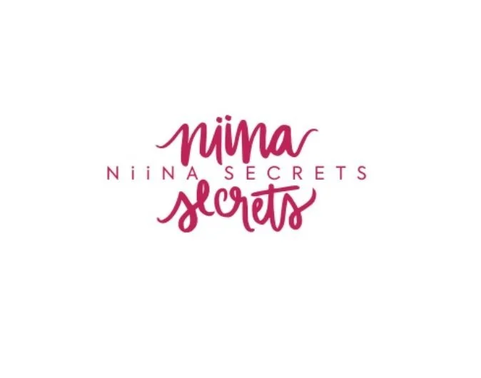 Logotipo com o texto 'Niina Secrets' em letra cursiva rosa escura, com fundo branco.