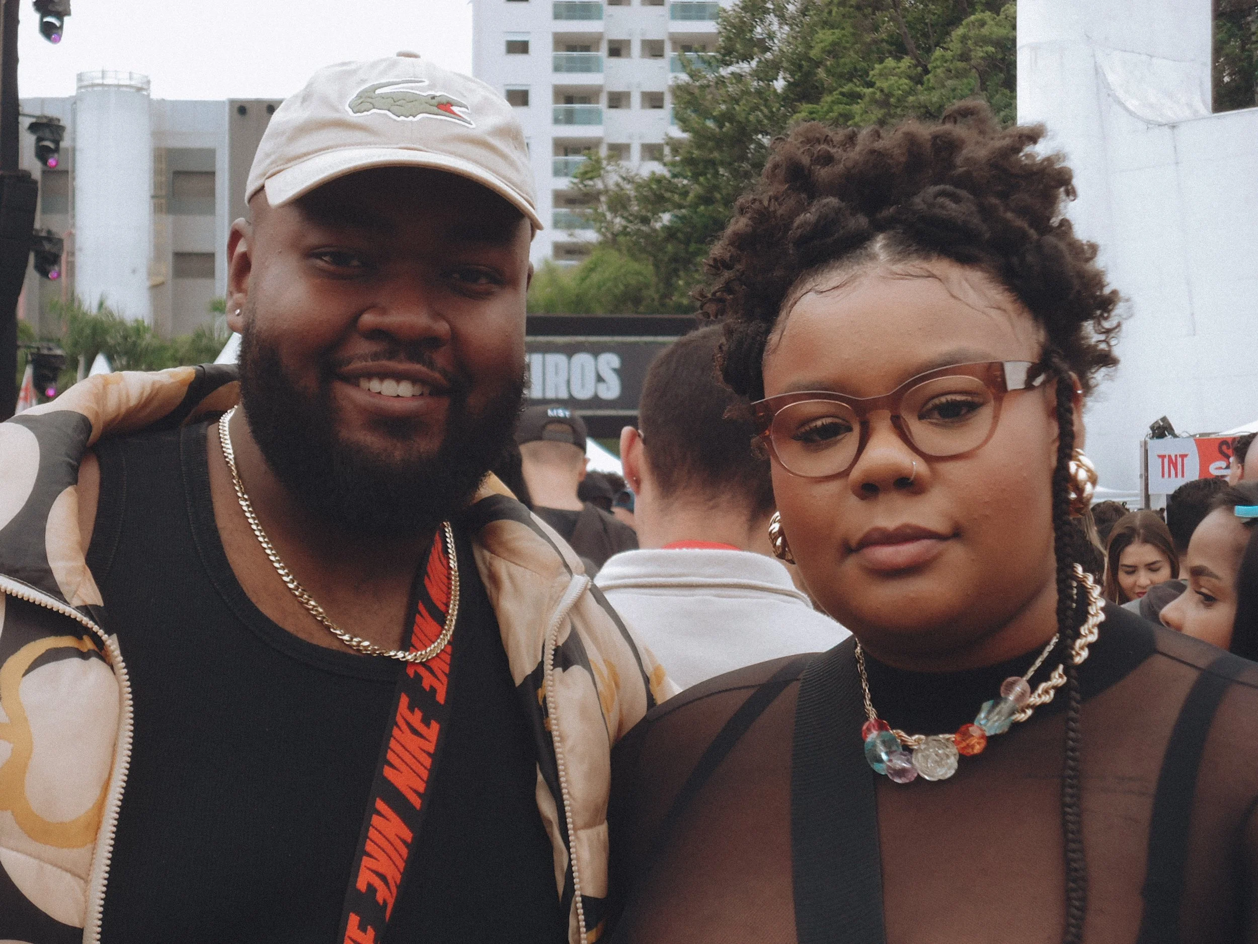 Homens e mulheres em uma praça urbana, com prédios ao fundo, sorrindo e posando para a foto.