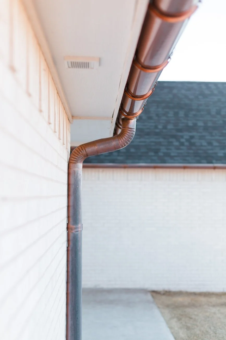 Close-up of copper gutter and downspout on brick house exterior.