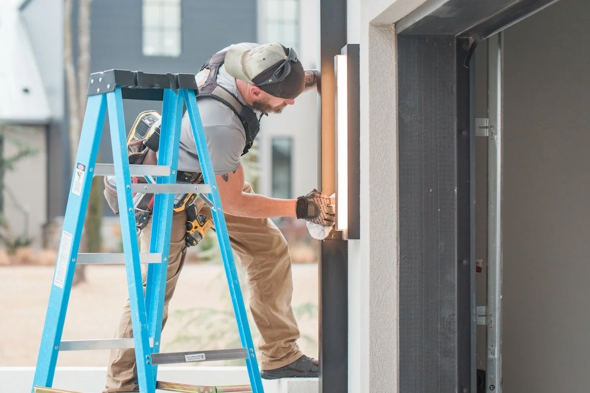 Electrician on ladder installing outdoor light