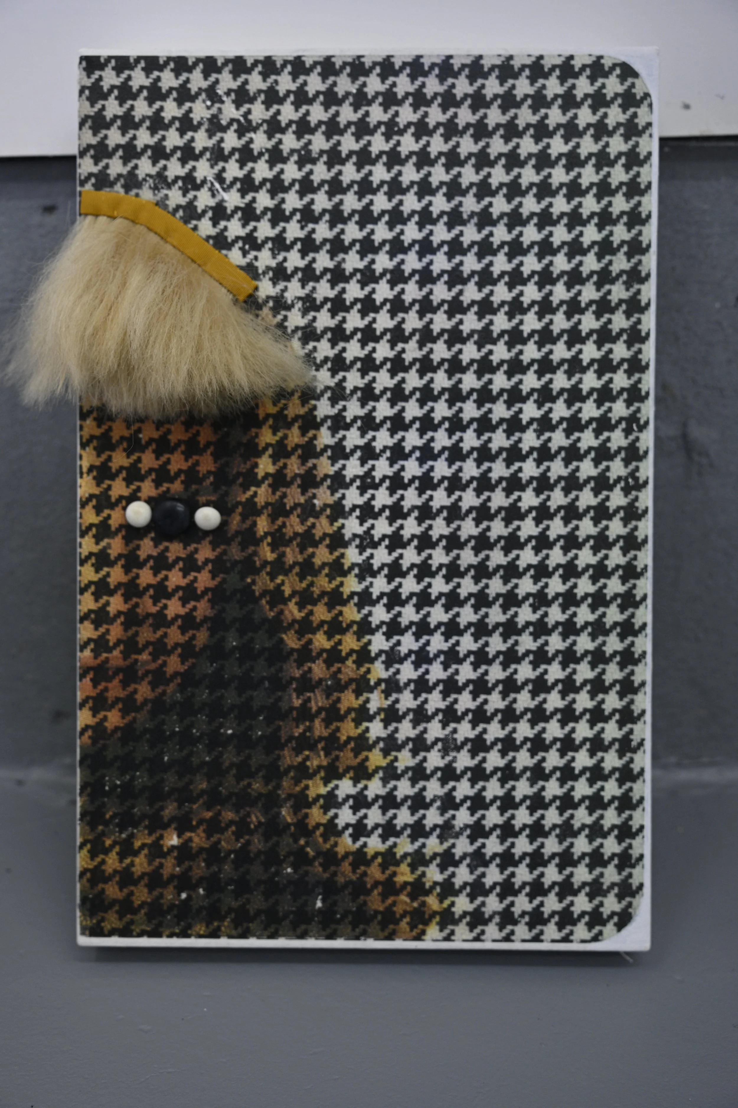 Houndstooth on Face / 2026 / acrylic transfers, buttons, Barbie hair, ribbon, thread on canvas / 17” x 11” / $1200