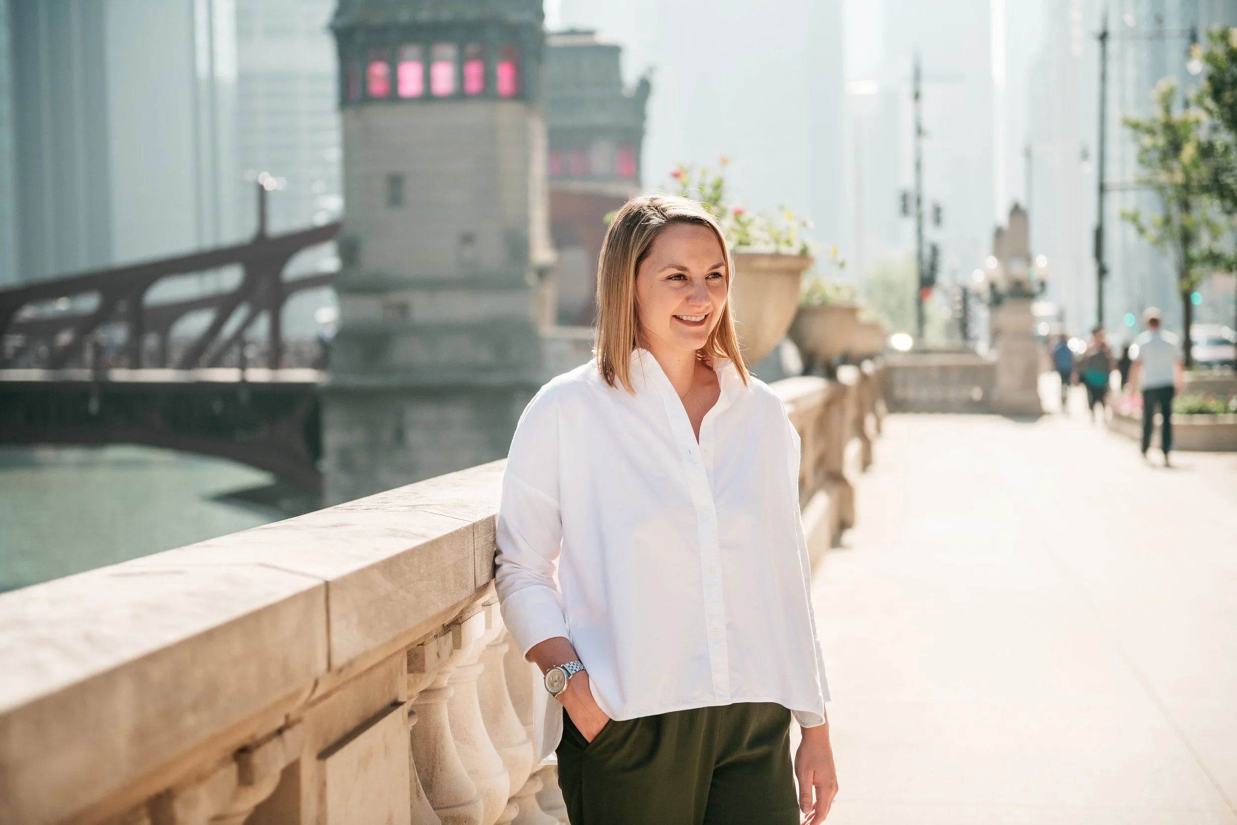 A woman sitting on a green sofa in a modern living room, smiling, with colorful abstract artwork on the wall behind her.