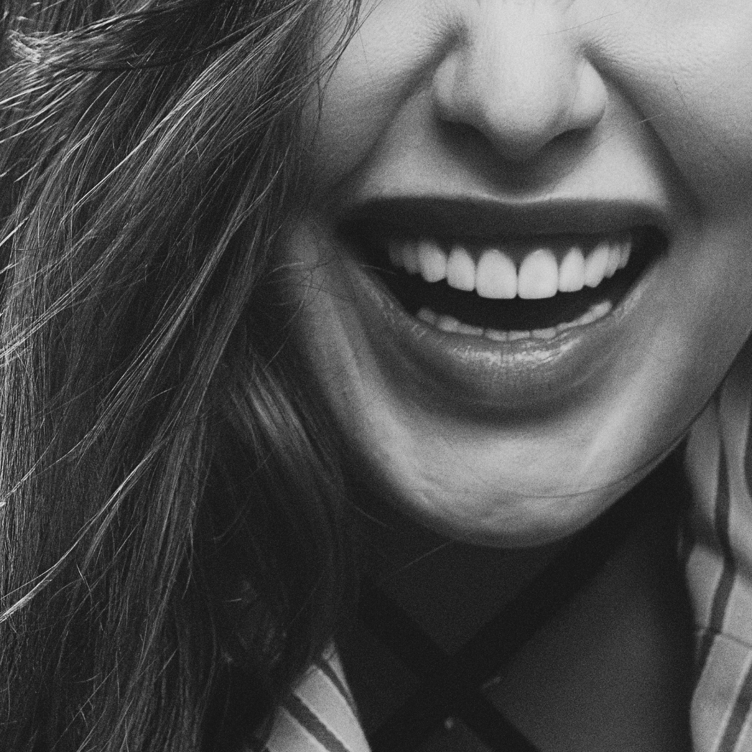 Close-up of a smiling woman with long hair in black and white.