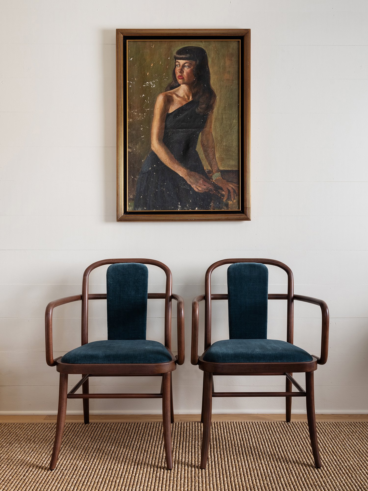 Pair of blue Trusty Dining Chairs against a white wall with a painted portrait above