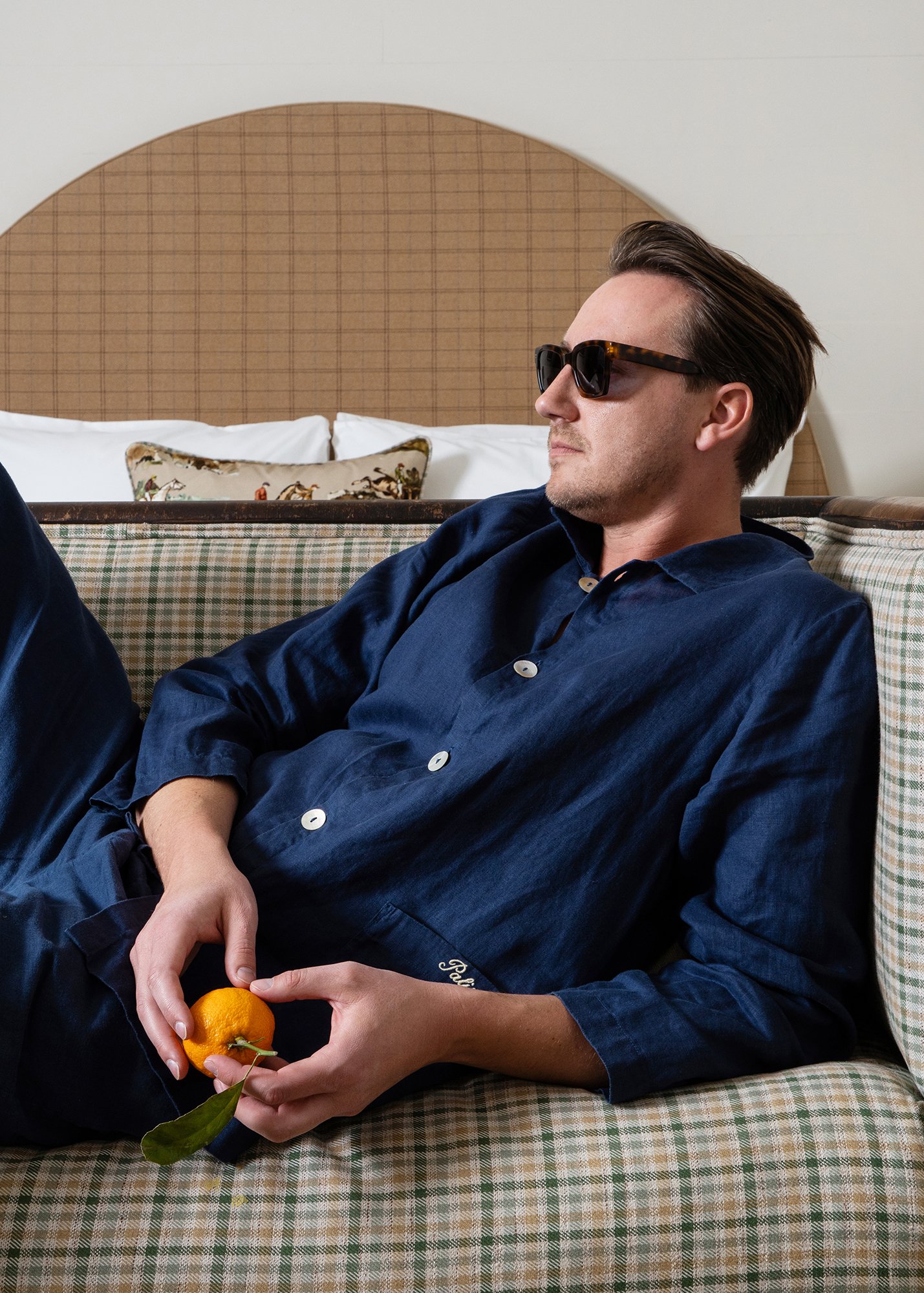 Model lounging on couch wearing Palisociety Navy Linen Pajamas