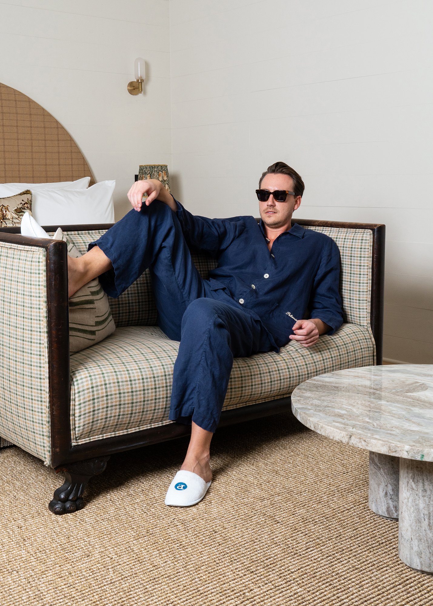 Model lounging on couch wearing Palisociety Navy Linen Pajamas