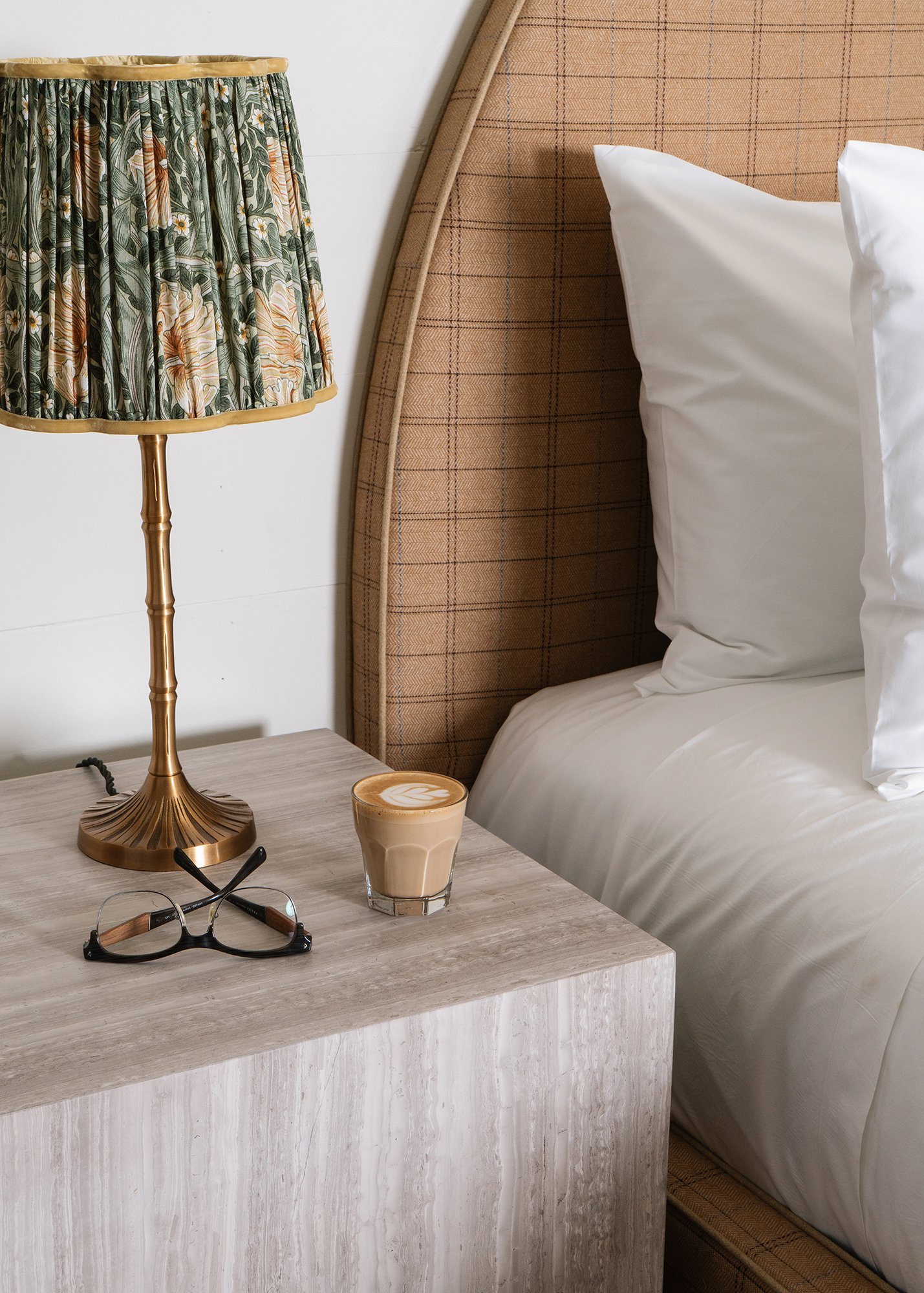 Detail view of top of Orlando Bedside Table that has a lamp, pair of reading glasses, and cup of espresso