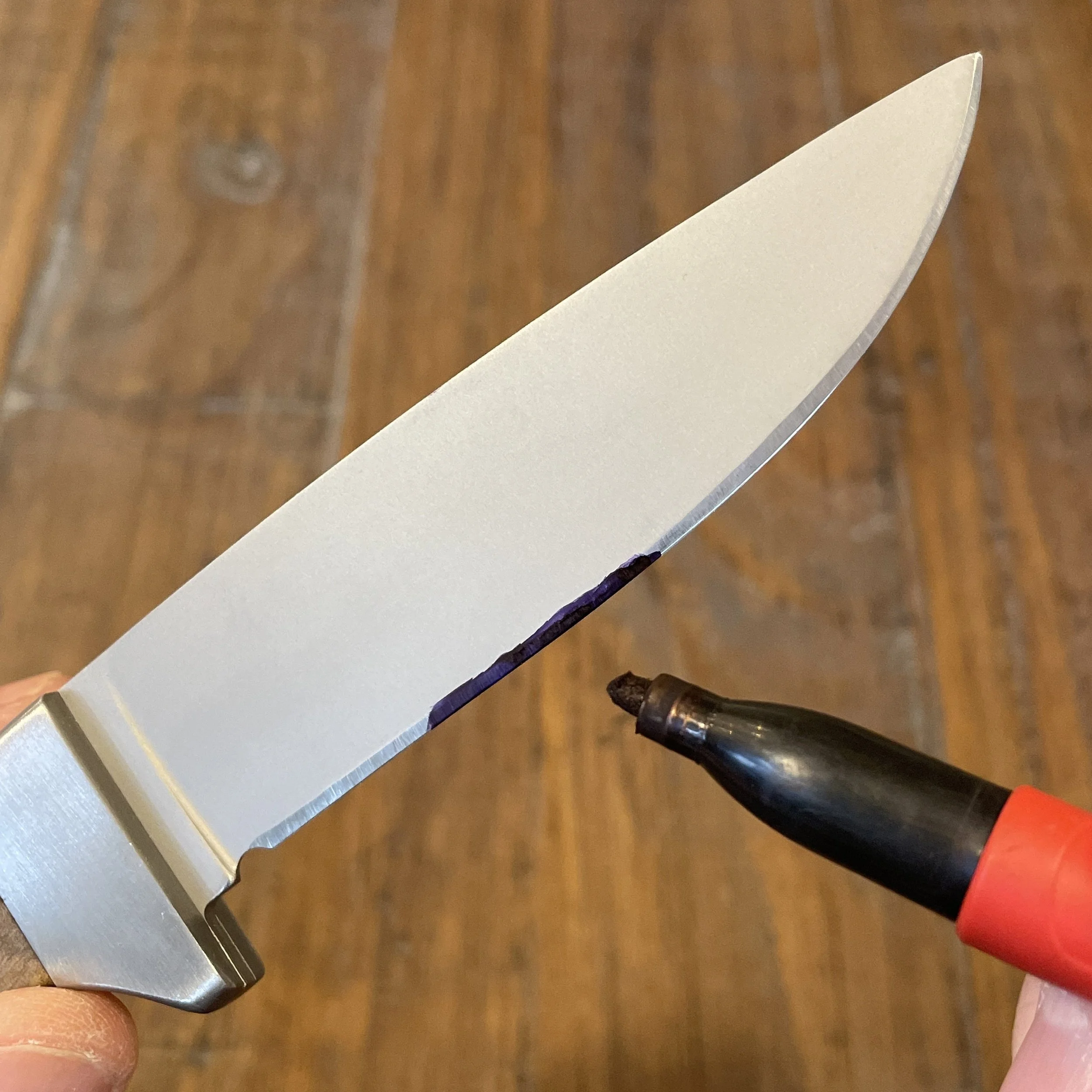 Applying permanent marker to the cutting edge of a knife is preparation for determining the most recent sharpening angle using a coin stack for reference.