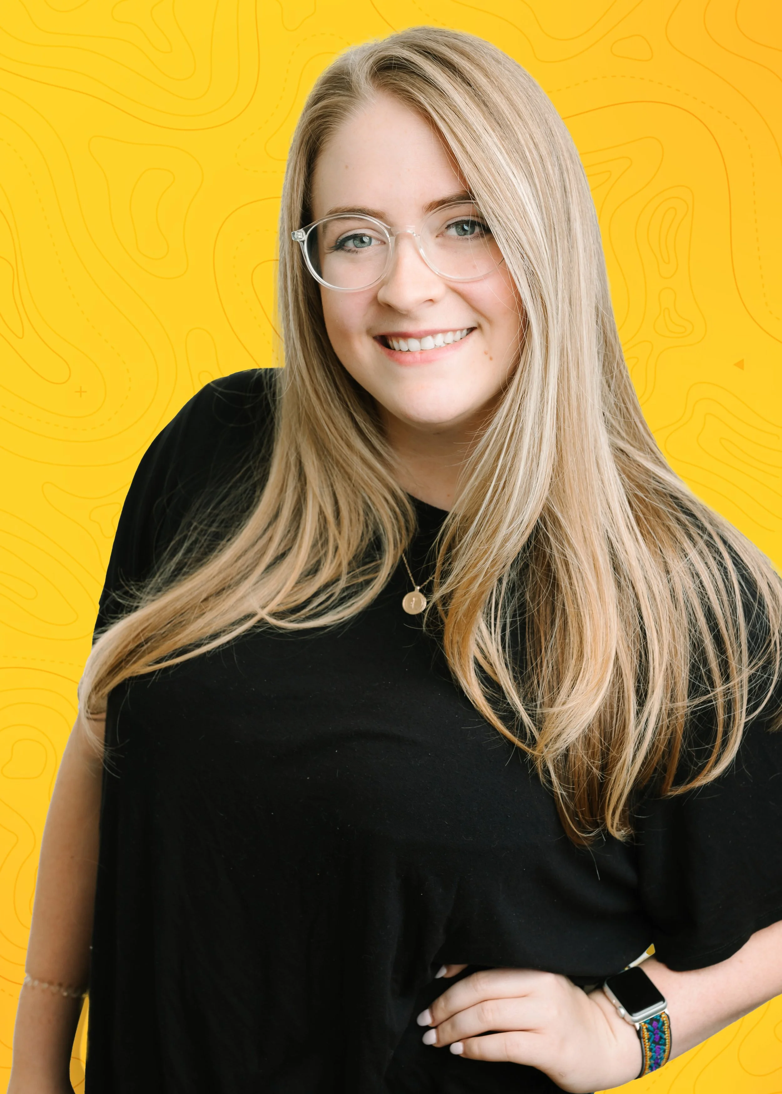 A smiling young woman with long blonde hair, wearing glasses, a black t-shirt, a necklace, a smartwatch, and a colorful bracelet, standing against a yellow background with abstract contour patterns.