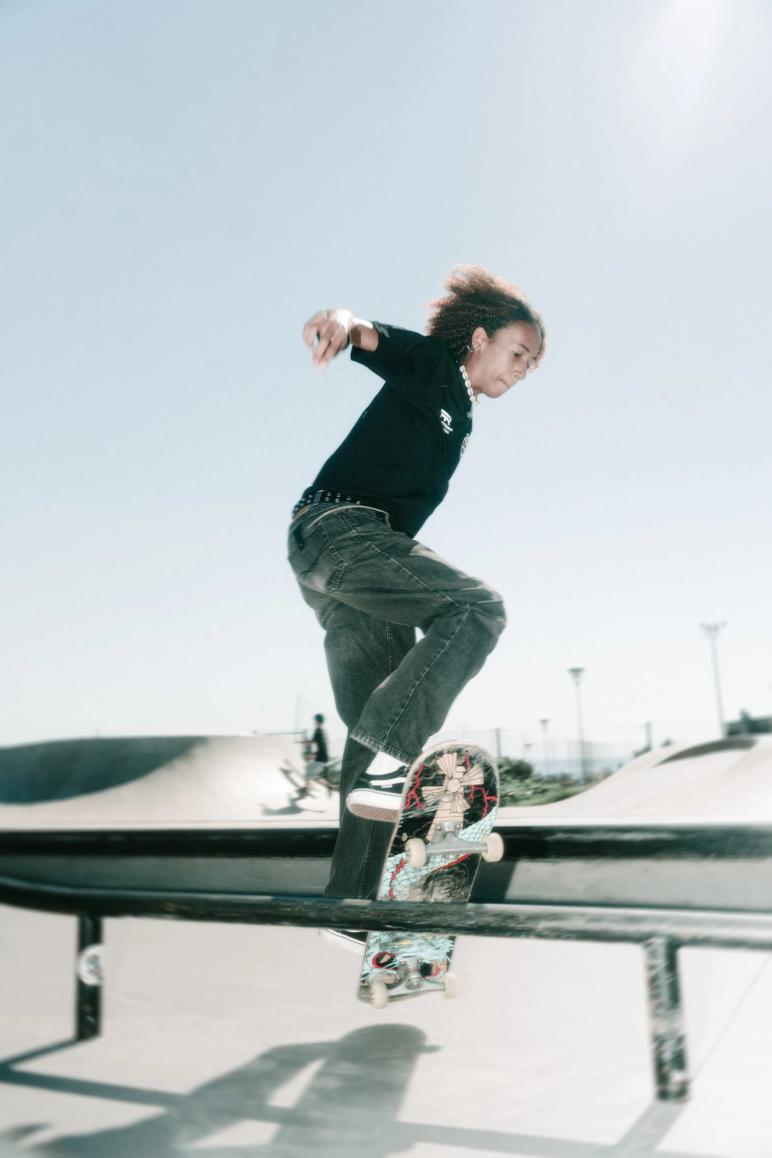 Joven practicando skate en un parque de patinaje al aire libre con cielo despejado.
