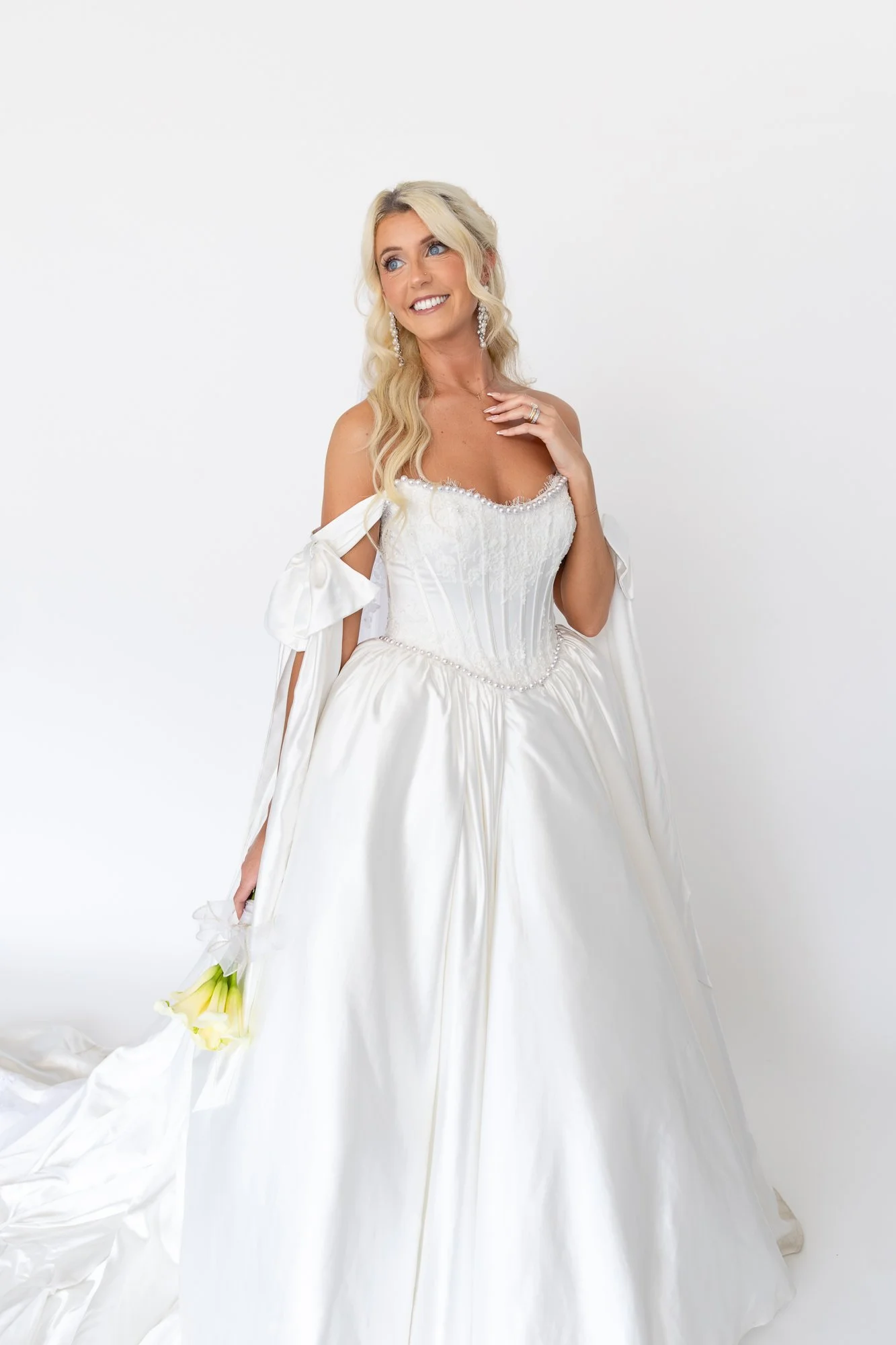 Candid portrait of bride in wedding dress on soft white backdrop. 