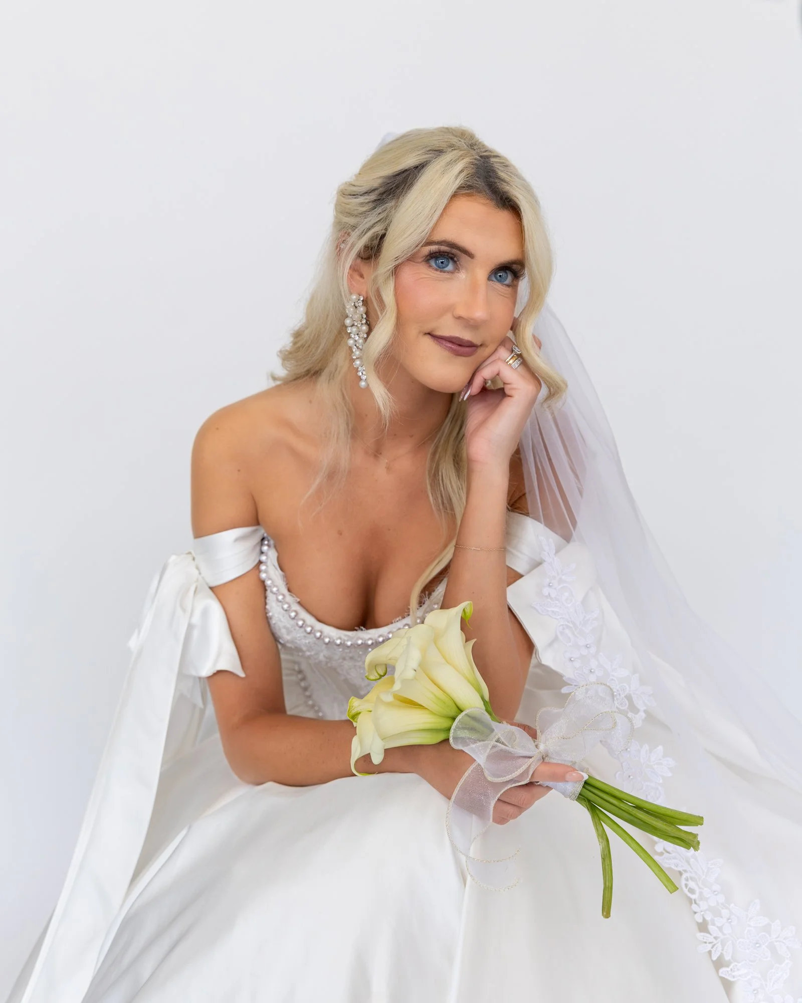 Candid photo of bride with hand on chin holding calla Lilly flowers