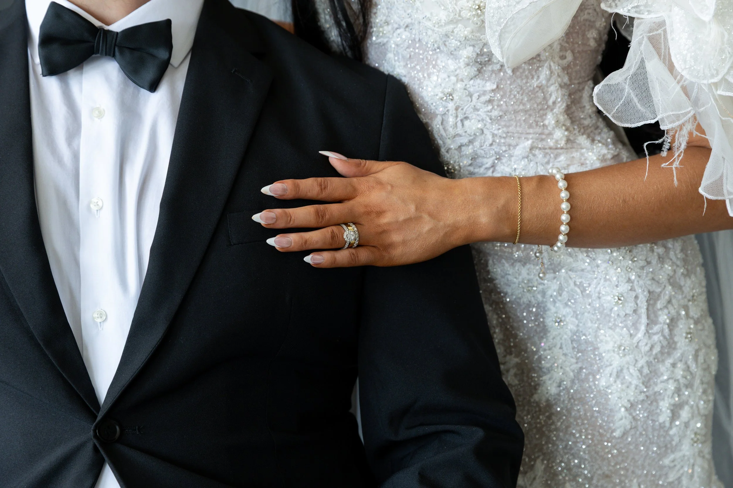 Detail shot of brides ring and grooms tuxedo.