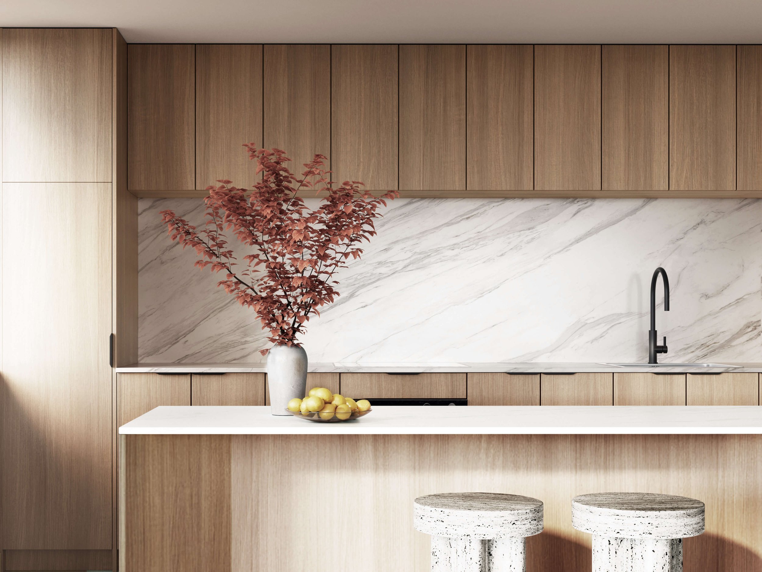 Modern kitchen with wooden cabinets, marble backsplash, black faucet, countertop with a vase of red leaves, bowl of lemons, and two round stools.