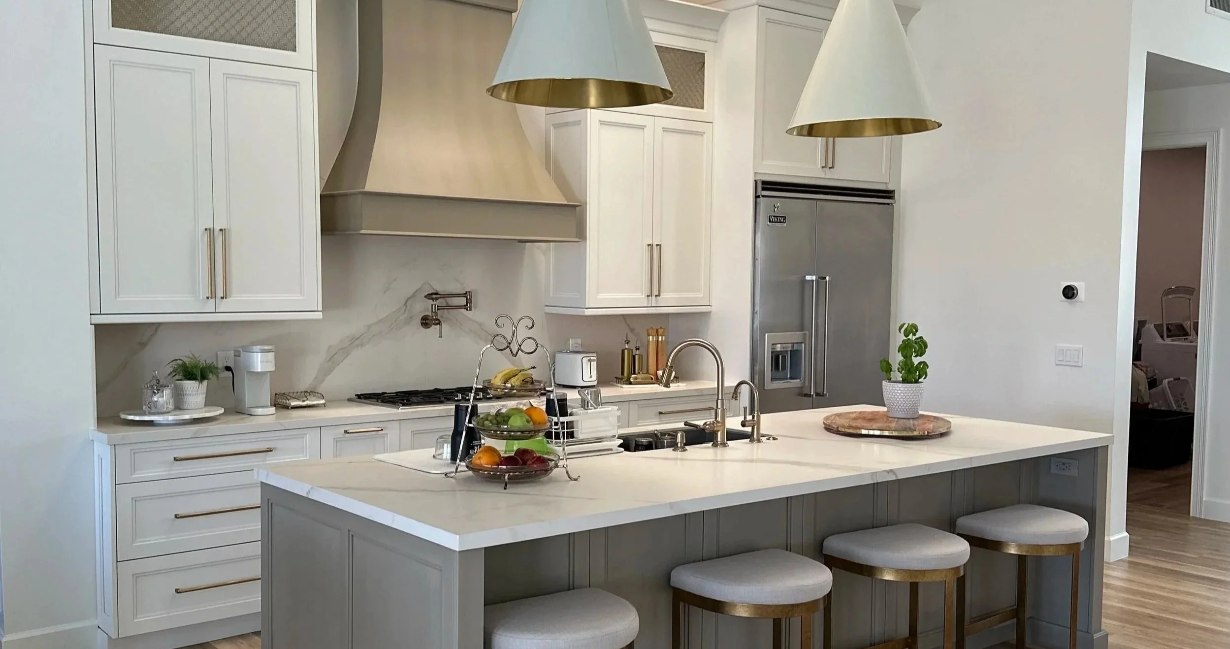 Modern kitchen with white cabinets, stainless steel appliances, a kitchen island with seating, two hanging pendant lights, and a skylight in the ceiling.