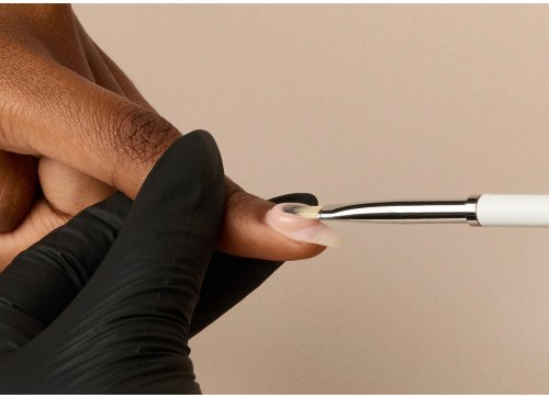 A person receiving a nail manicure with a nail polishing tool.