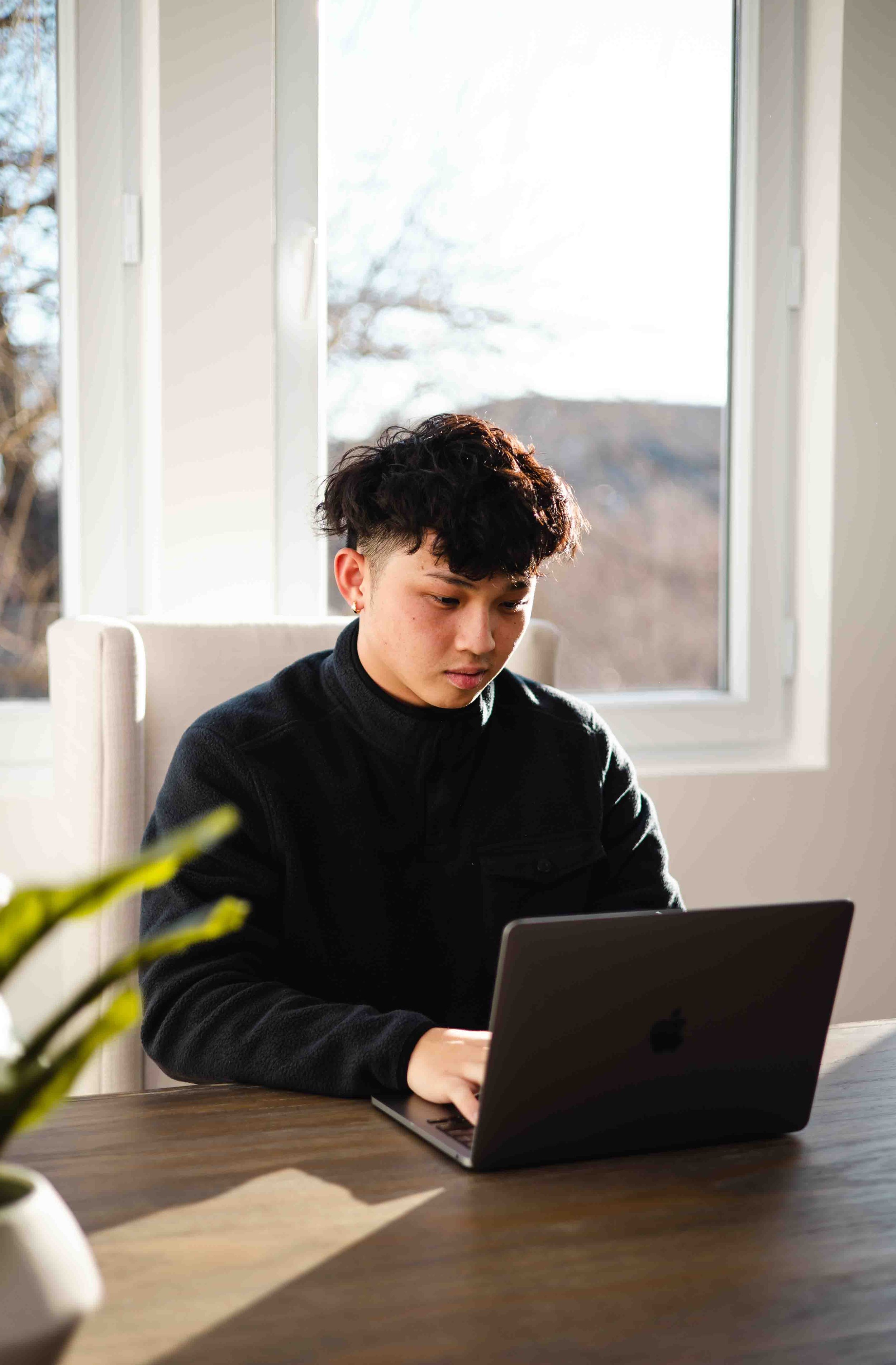 Person using a laptop in a bright room with a window view.