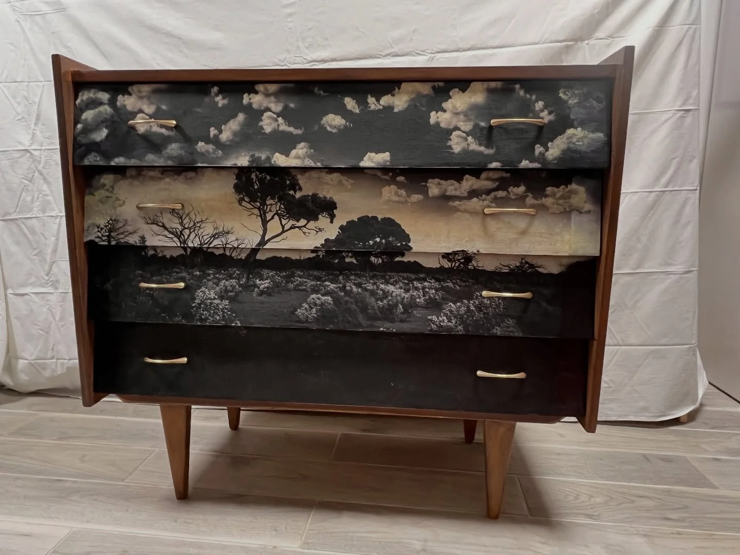 Before &rarr; After.

This mid-century chest of drawers has lived a few lives, just like me!

Inspired by the Australian landscapes where I spent the last 15 years, I transformed this vintage piece into a panoramic scene: dramatic skies, lonely trees