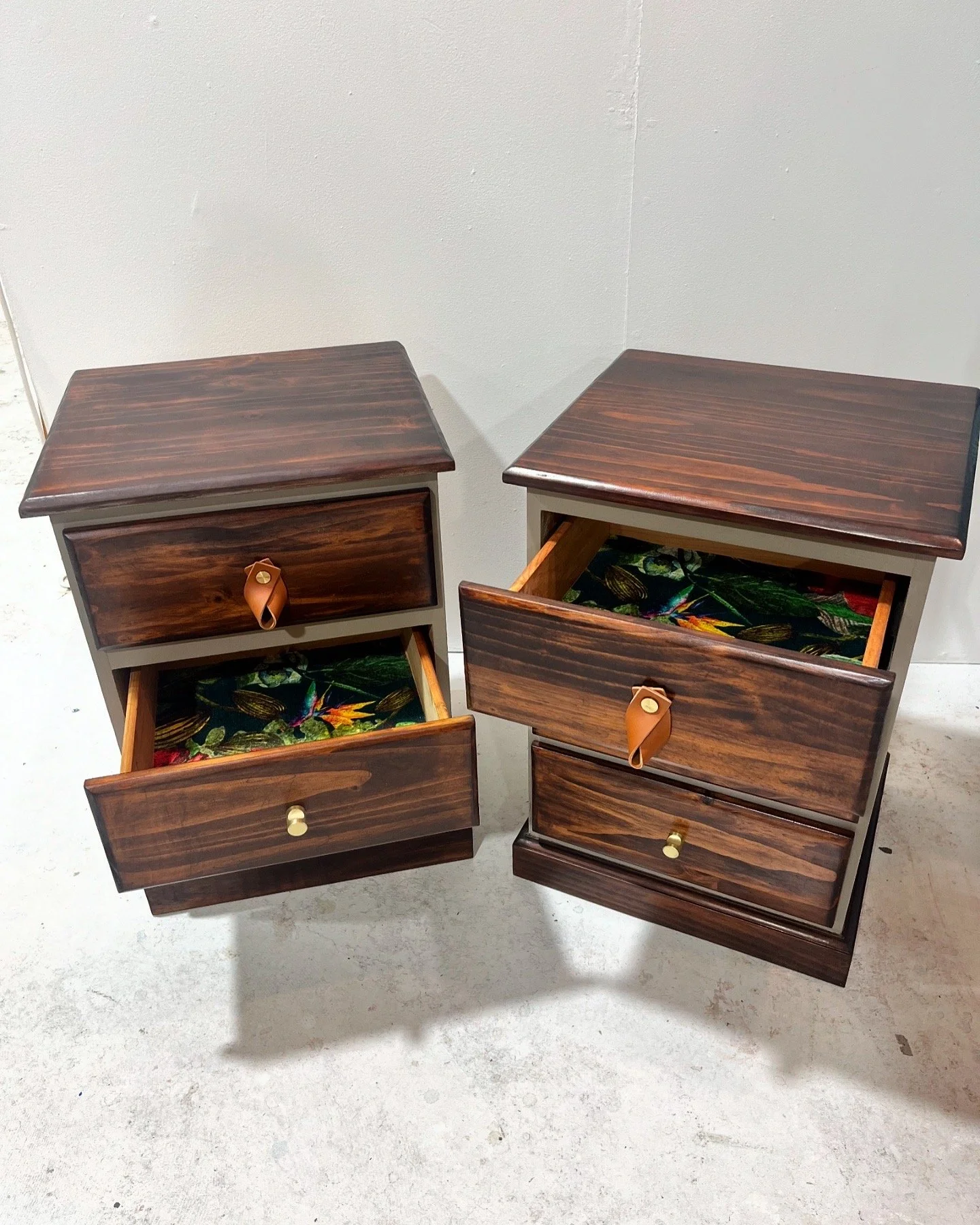 Two wooden nightstands with open drawers, displaying floral-patterned lining.