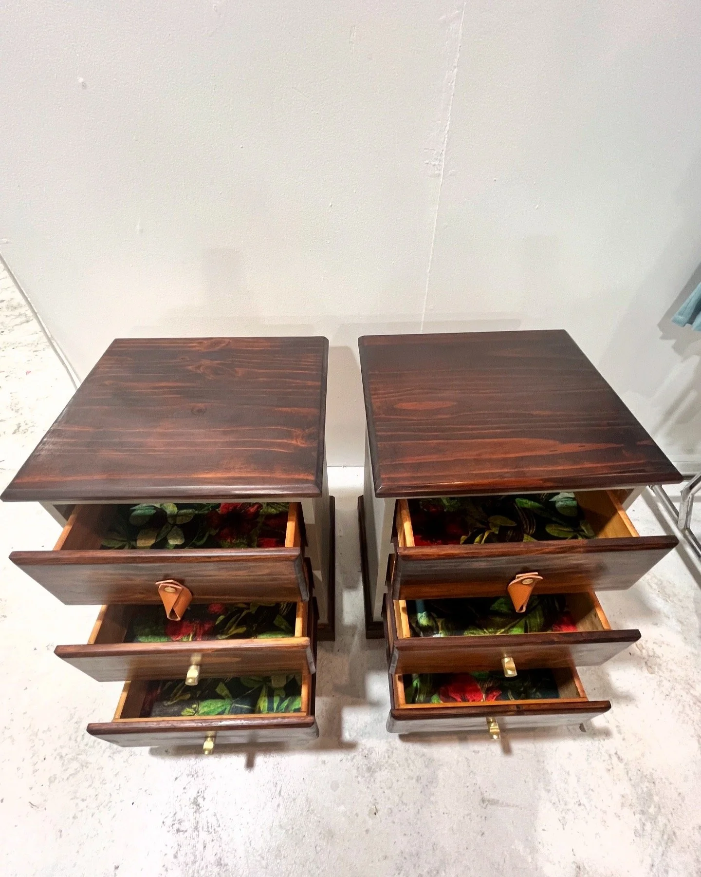 Two dark wooden nightstands with three drawers each, featuring floral-patterned drawer liners.