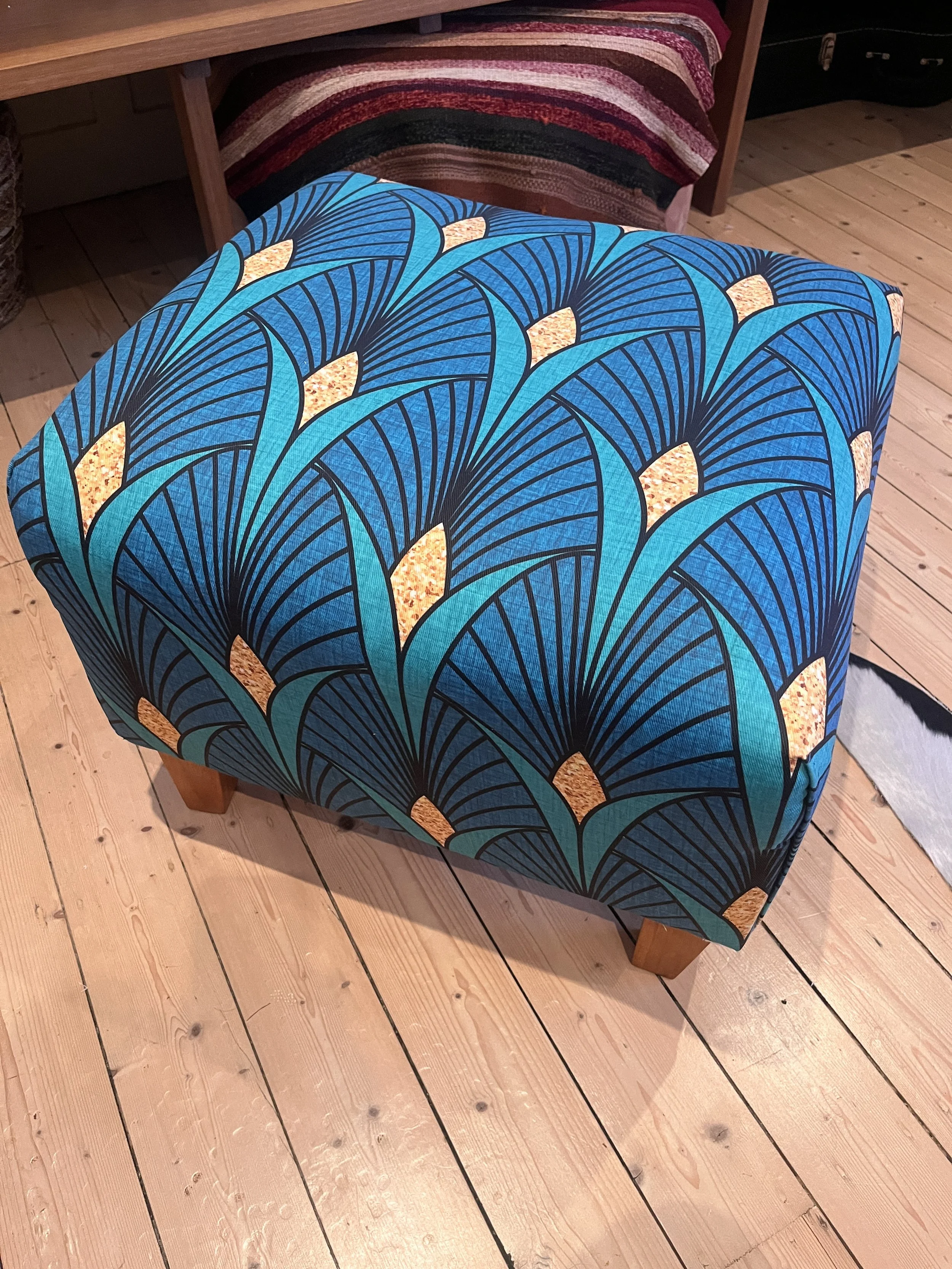 Colorful patterned ottoman on a wooden floor.