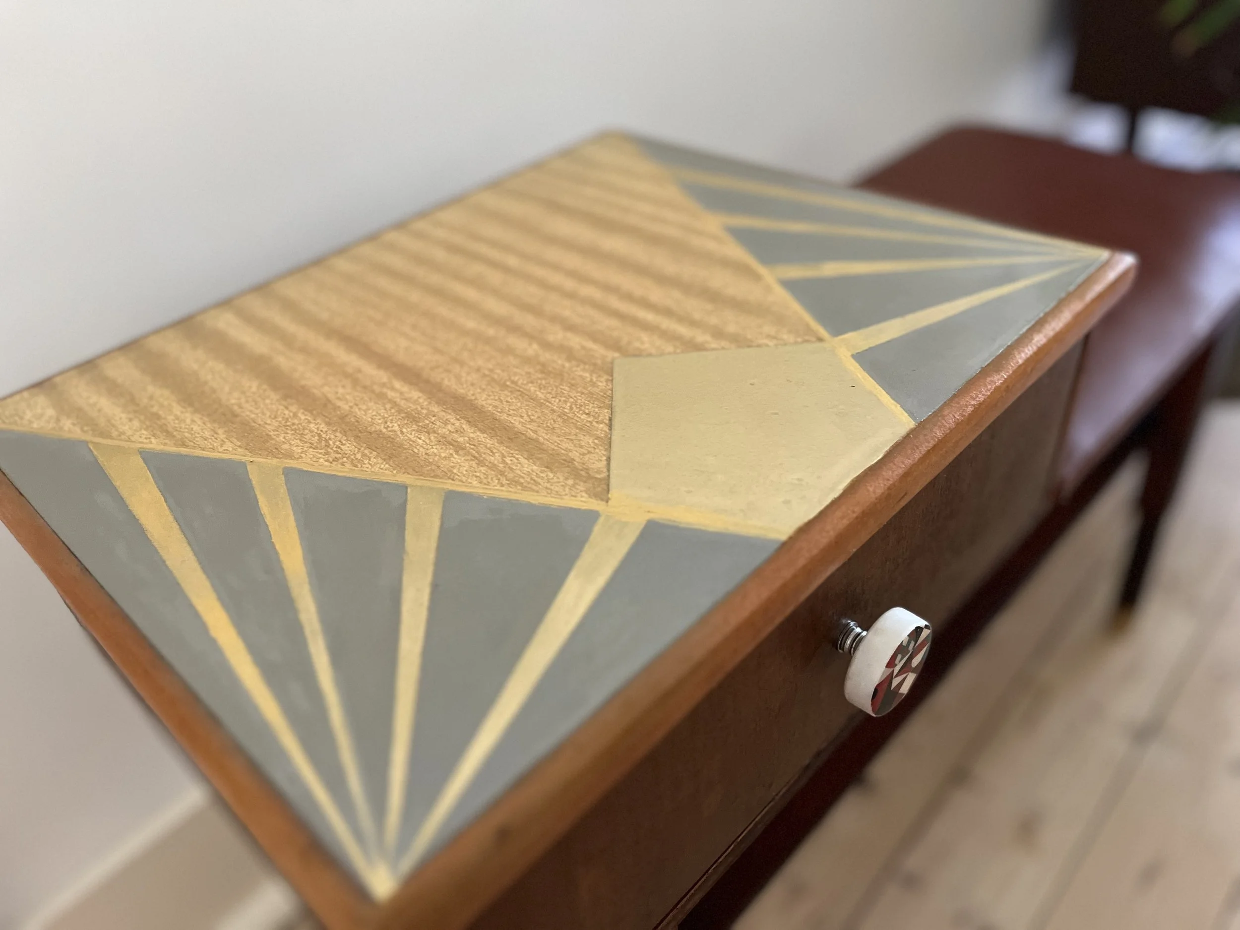 Decorative tabletop with geometric art and a drawer with a patterned knob.