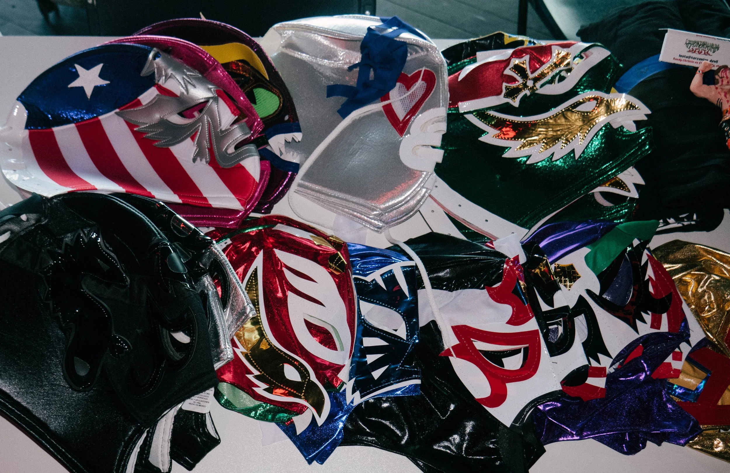 A collection of colorful superhero masks, including designs with stars, stripes, and metallic finishes, displayed on a table.