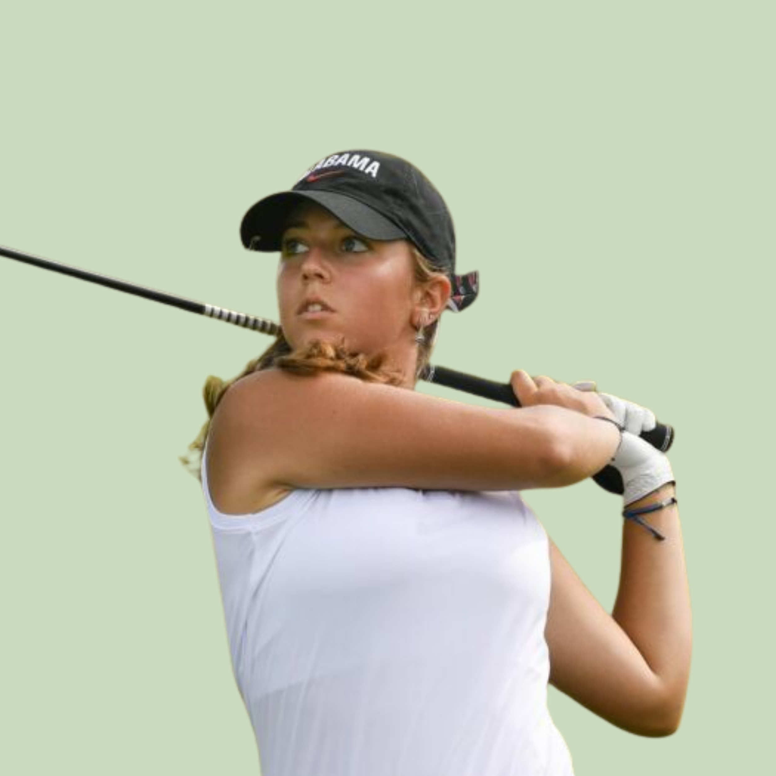 Close-up of a female golfer, wearing a black cap with 'BAMA' written on it, preparing to hit a golf shot, with her eyes focused and holding a golf club.