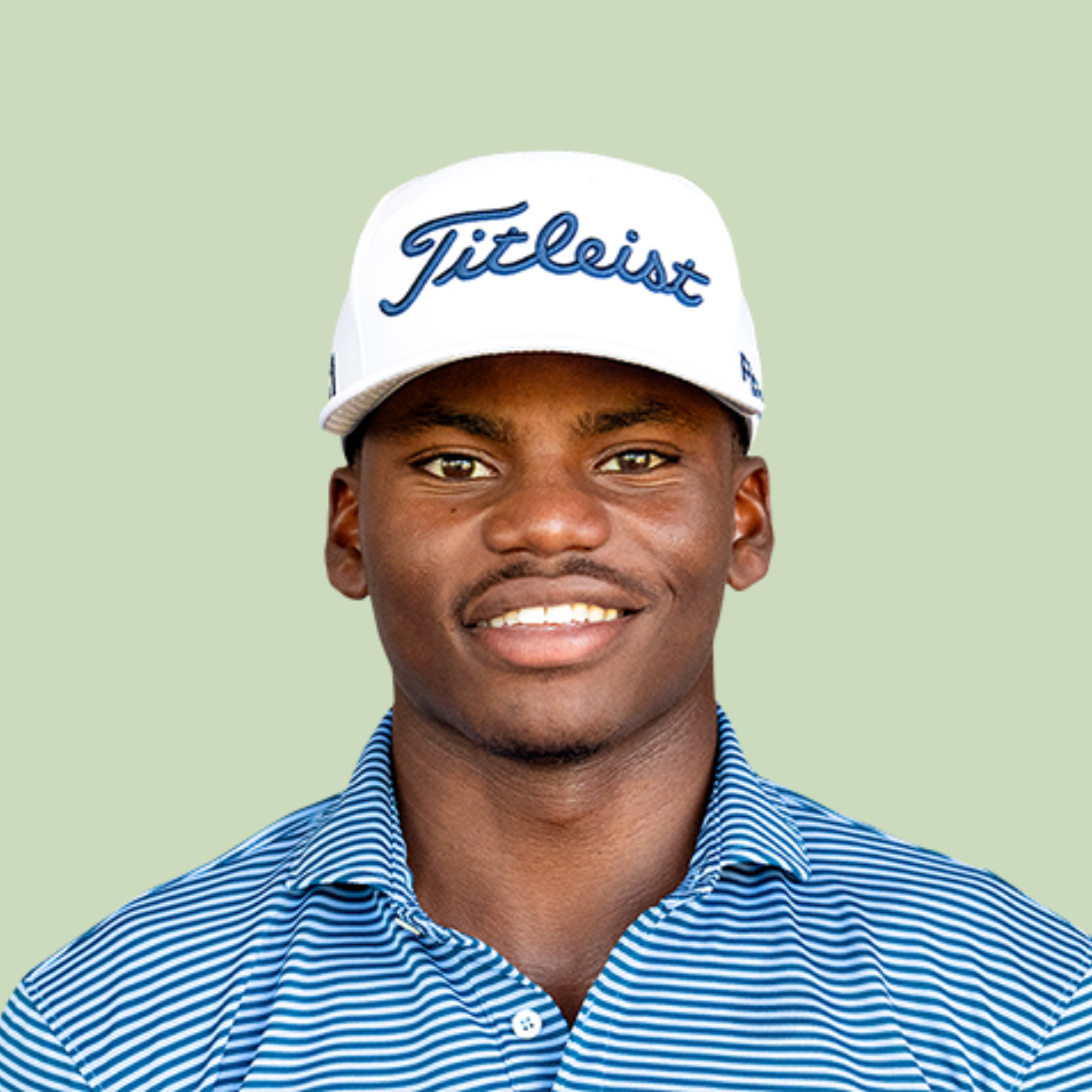 Close-up of a smiling young man wearing a white baseball cap with the word 'Titleist' embroidered in blue on it, and a blue and white striped shirt, against a light green background.