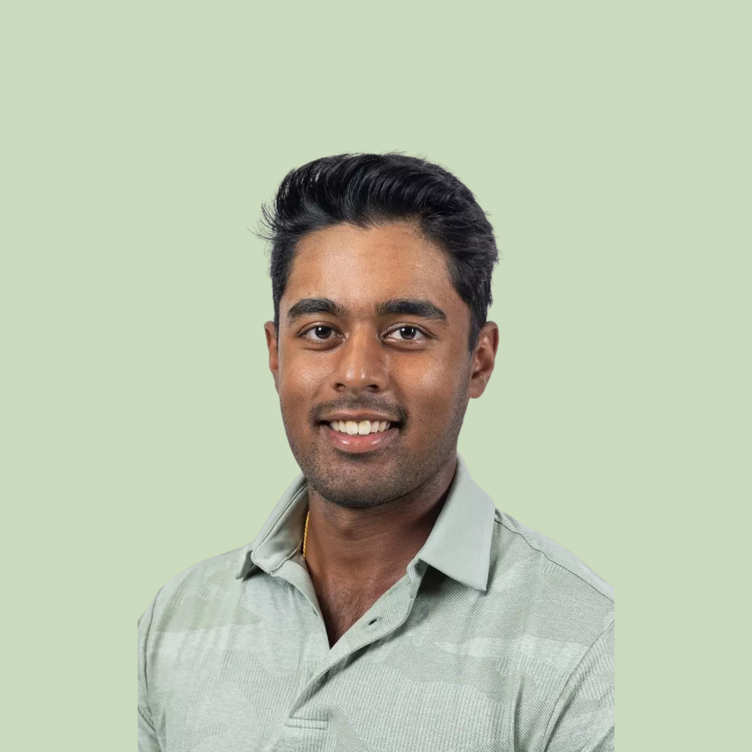 Close-up of a smiling man with short dark hair, wearing a light-colored collared shirt, against a pale green background.