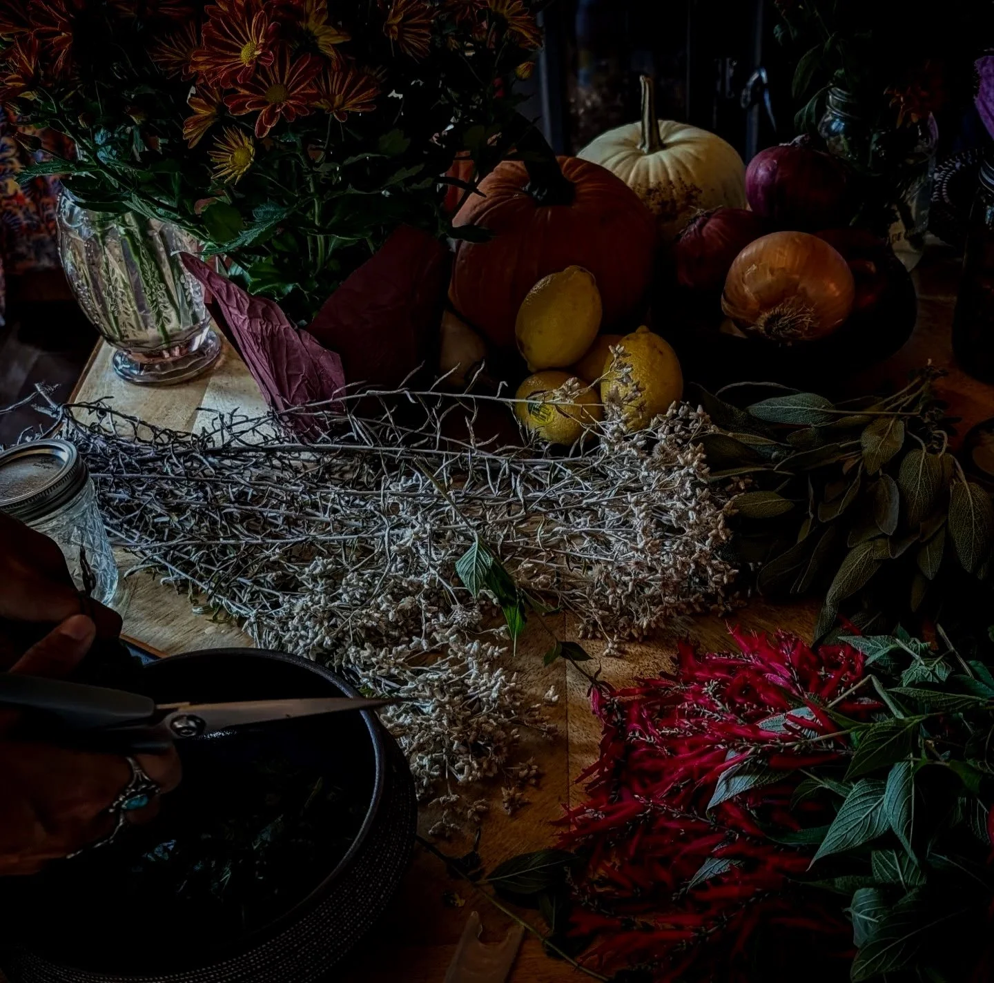 Arrangement of fall decor including pumpkins, lemons, flowers, dried branches, and leaves on a wooden table.