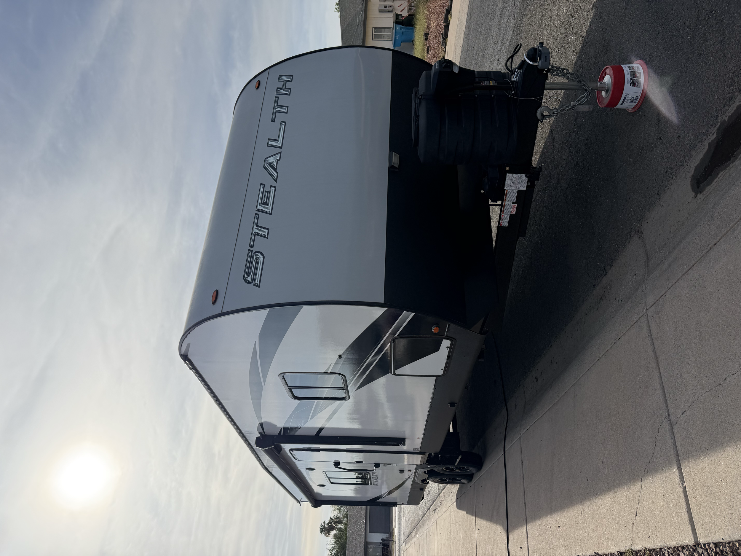 A white travel trailer with black accents and the brand name 'Sovereign' on the side, parked outside on a cloudy day.